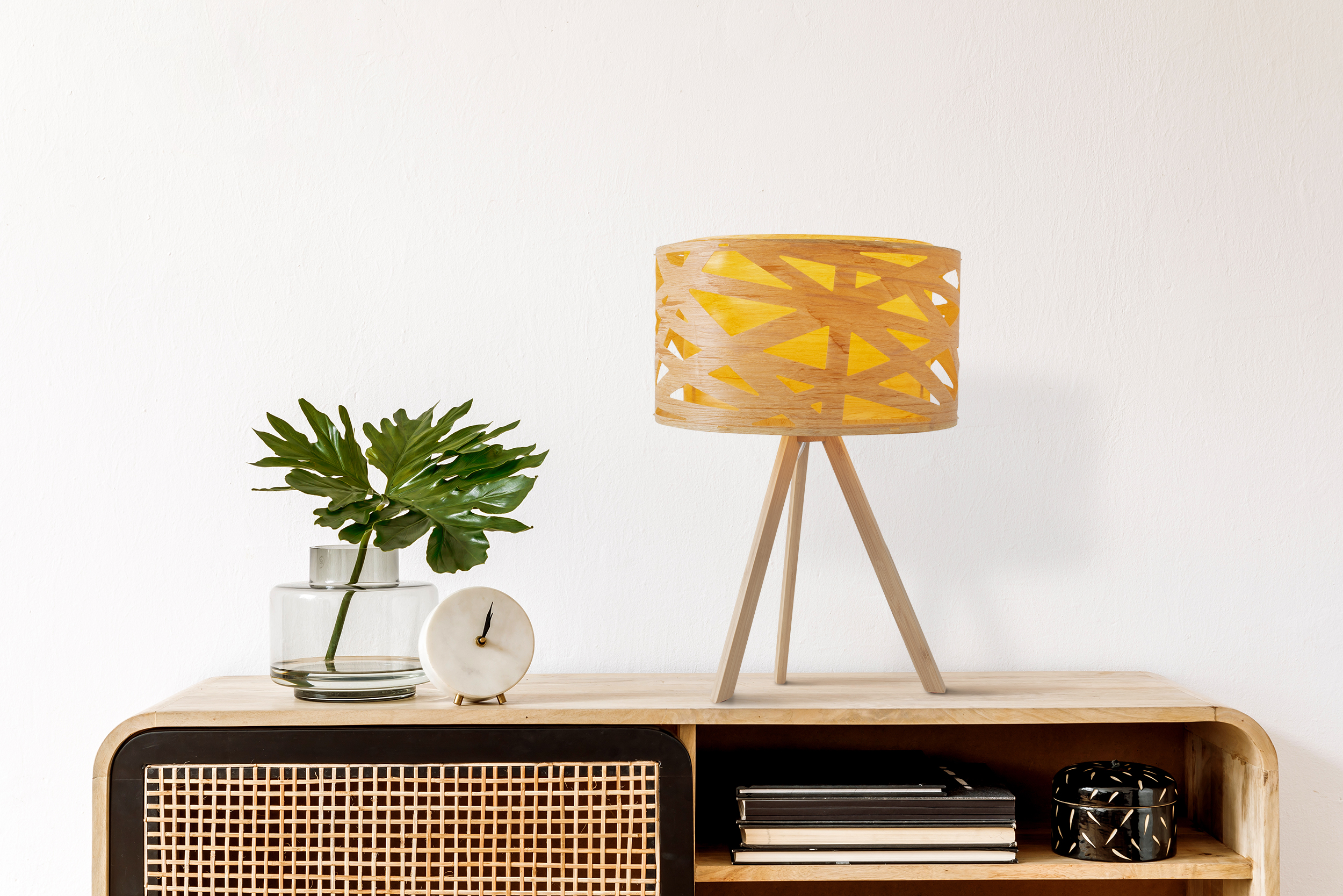 Holztischlampe mit gelbem Innenraum und eine Vase mit Pflanze, eine Uhr und Bücher auf einem Schrank.