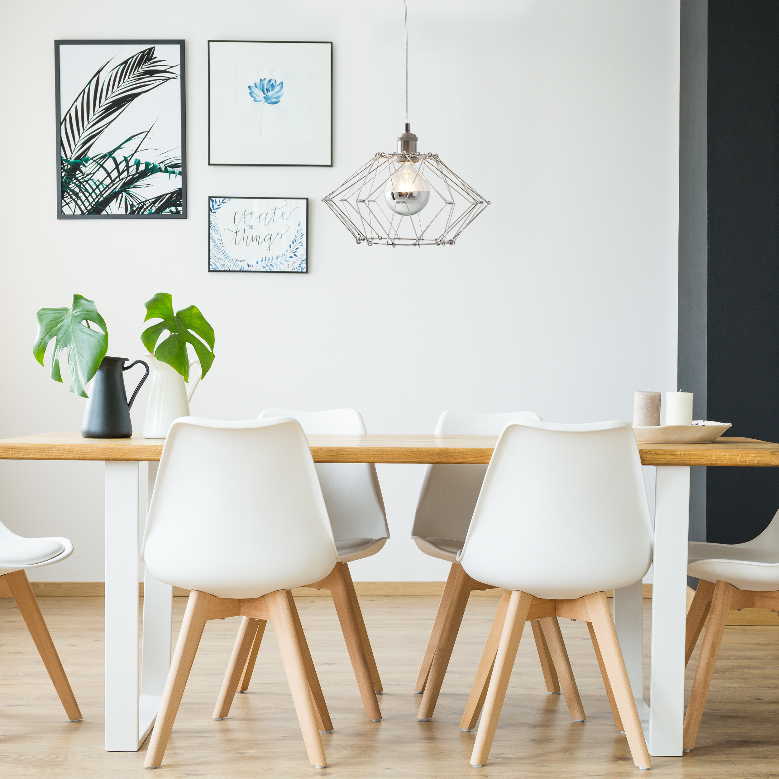 Esszimmer mit Holztisch, weißen Stühlen und Wandkunst.
