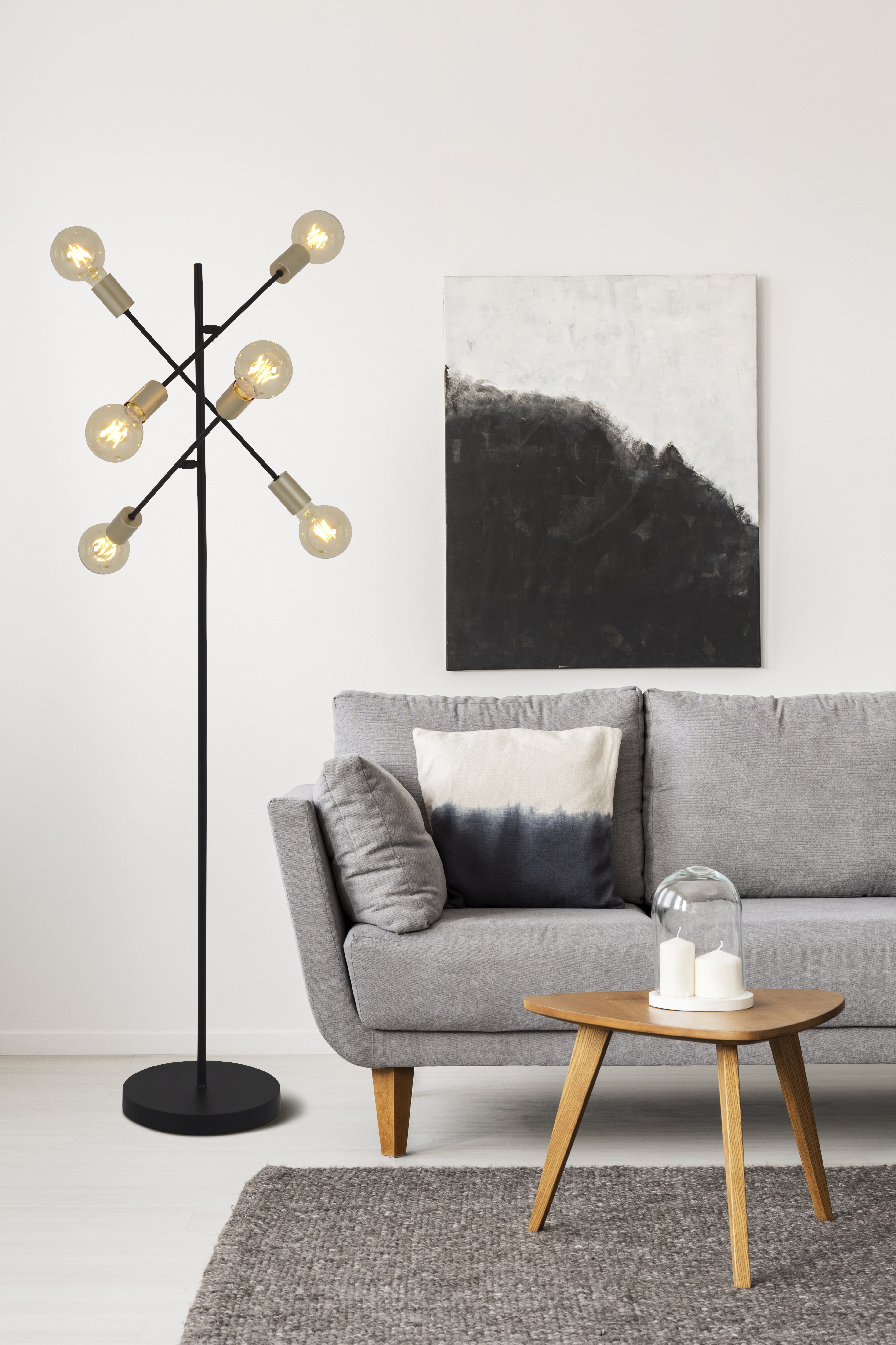 Eine Stehlampe mit sechs Glühbirnen. Es befindet sich in einem Wohnzimmer mit Sofa und Gemälde.