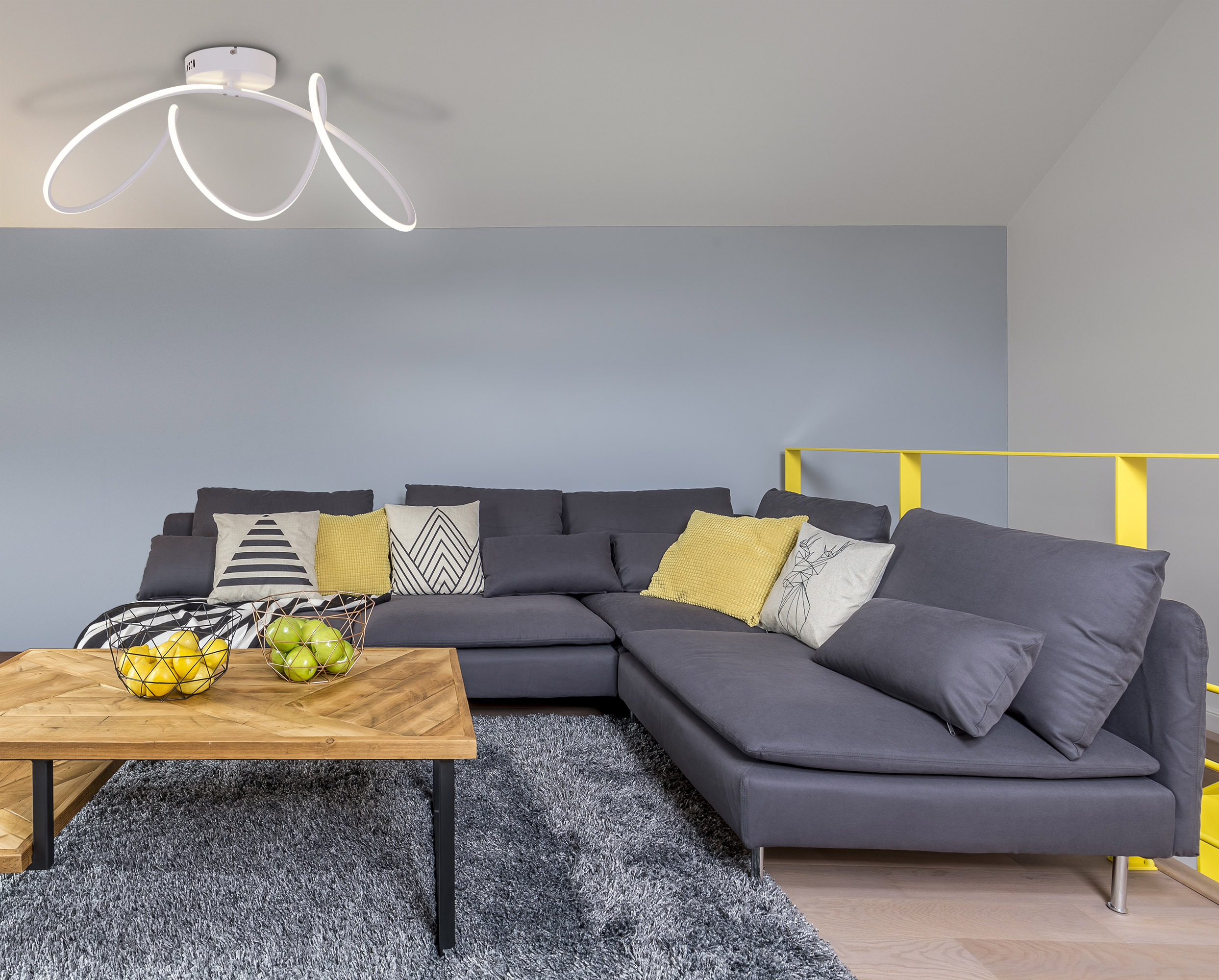 Modernes Wohnzimmer mit grauem Sofa, Holztisch und einzigartigem Licht.