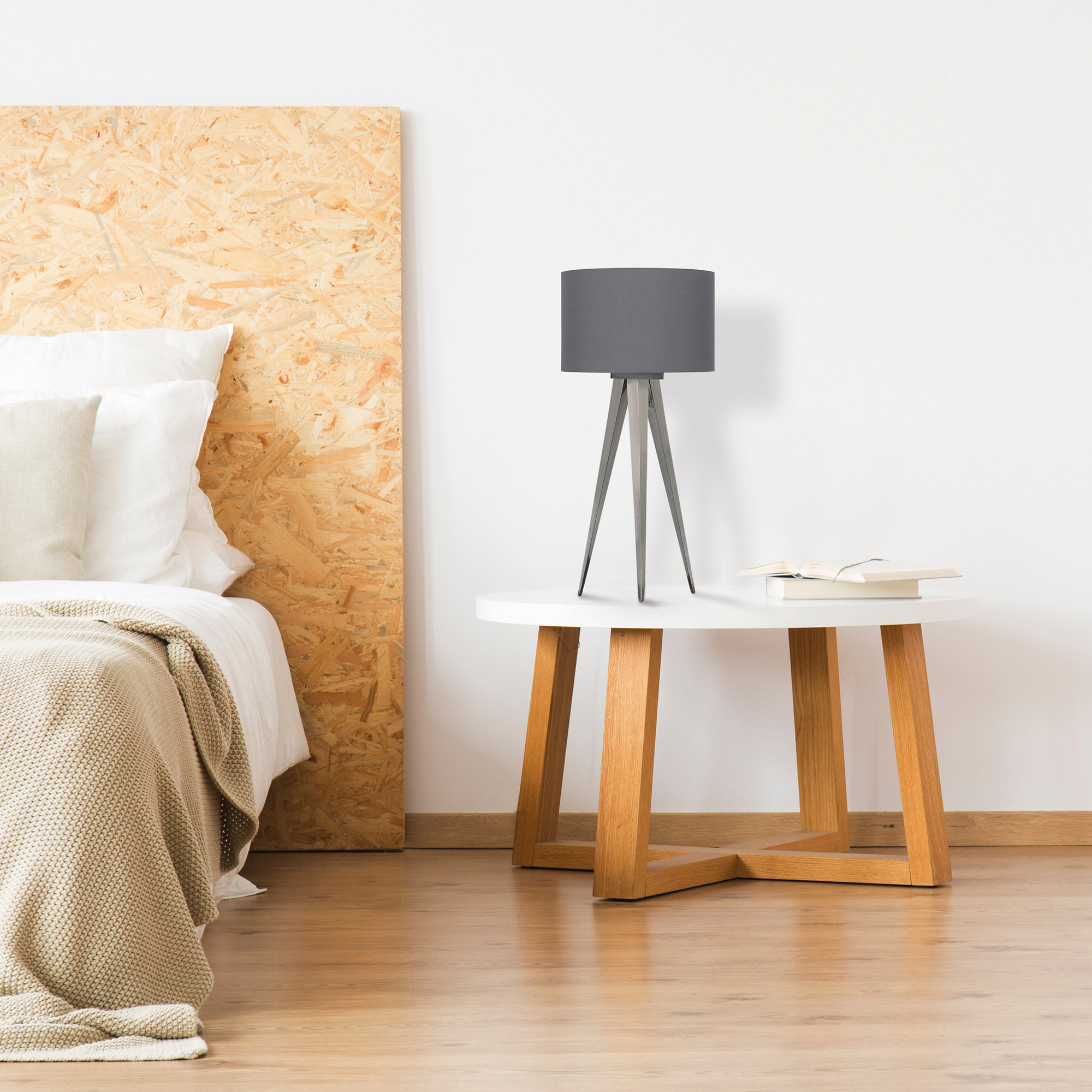 Schlafzimmer mit Bett, Beistelltisch und grauer Lampe, mit Holzboden.