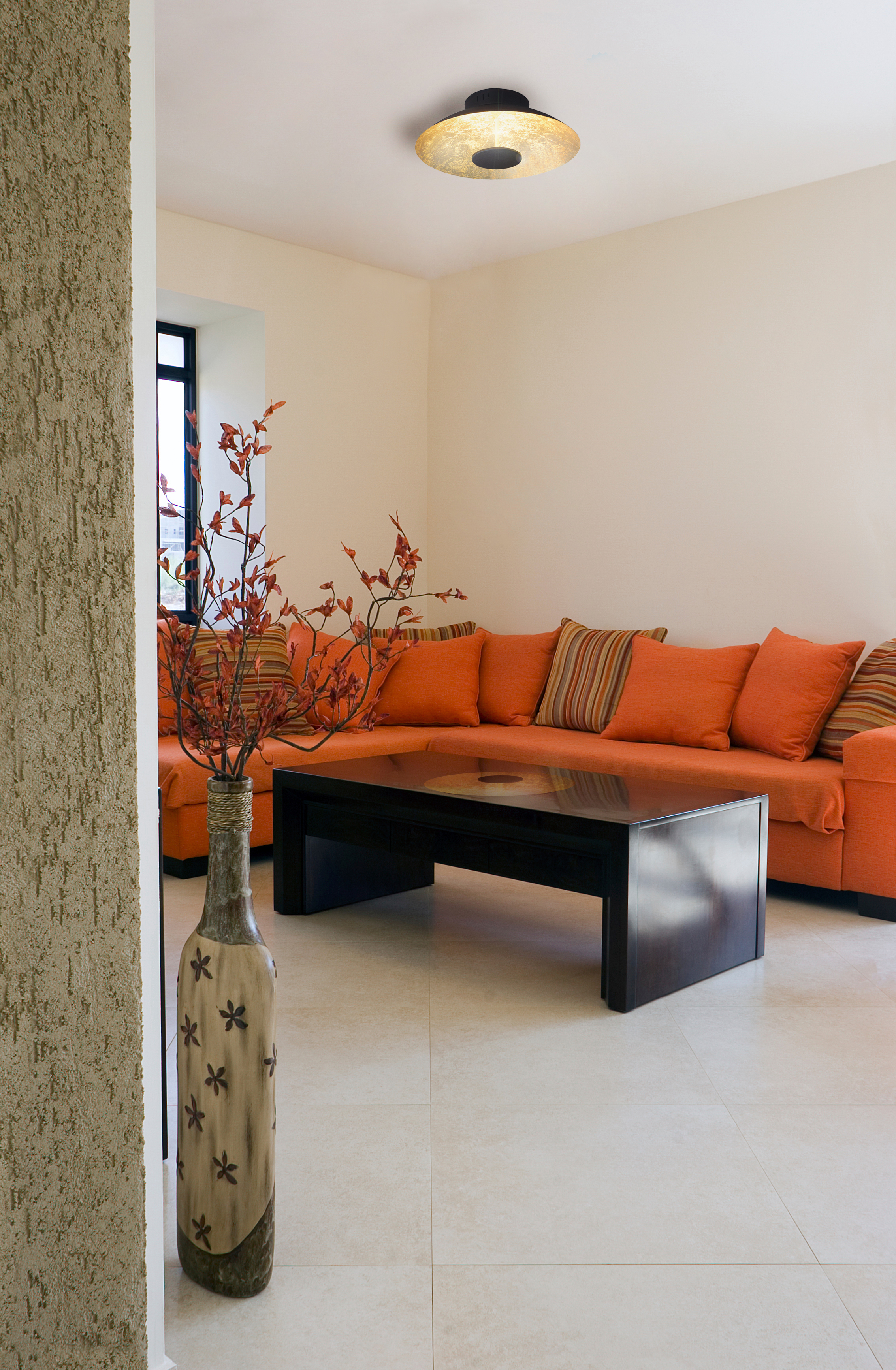 Innenwohnzimmer mit orangefarbenem Sofa, schwarzem Tisch, Vase und Deckenleuchte.