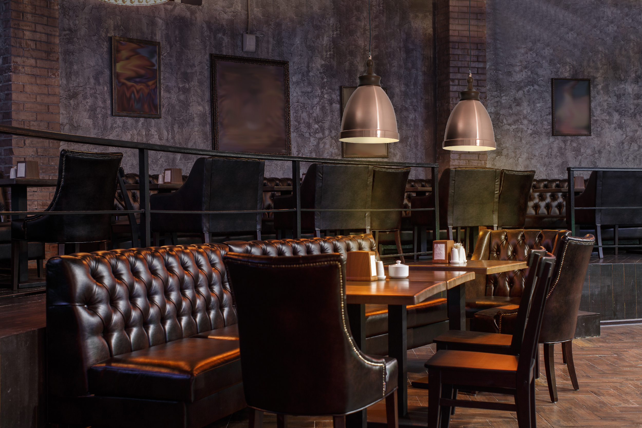 Innenraum eines Restaurants mit Tischen, Stühlen und Lampen an der Decke.