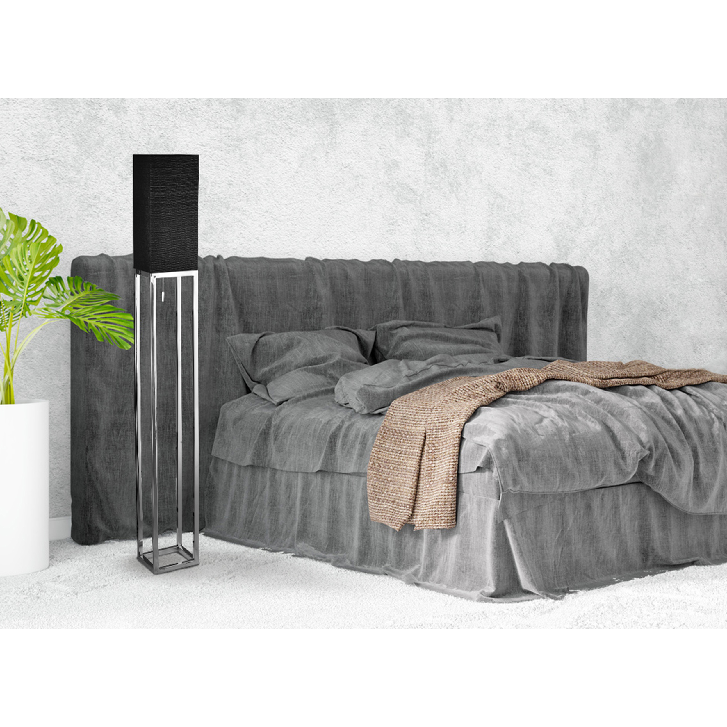 Graues Bett mit Decke und Stehlampe neben weißer Wand.