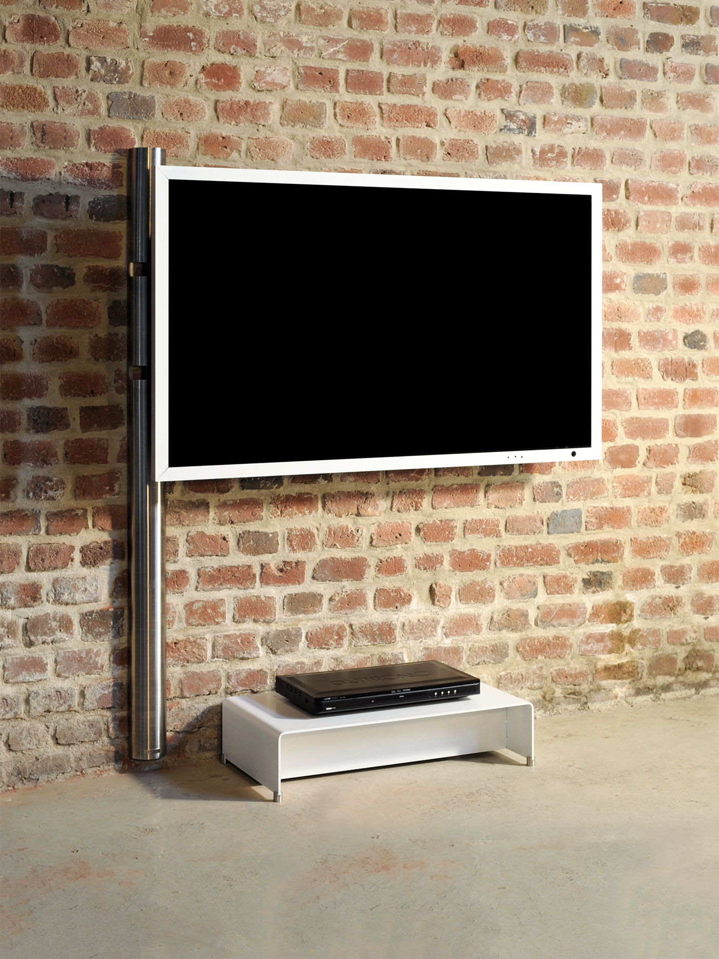 Ein wandmontierter Fernseher über einem weißen Ständer, vor einer Backsteinmauer.