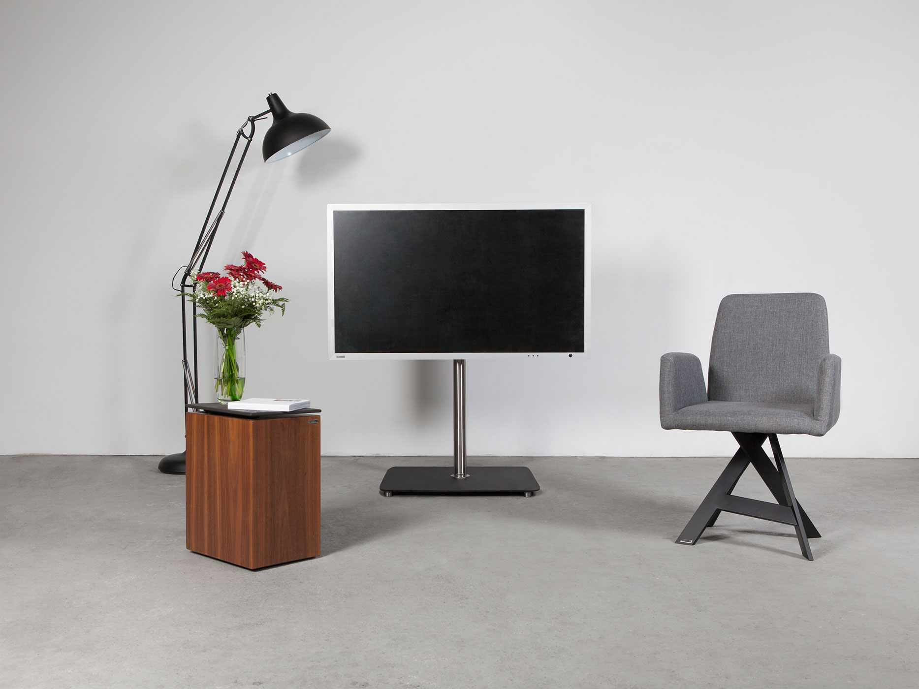 Ein modernes Wohnzimmer mit einem Fernseher auf einem Ständer, einem Beistelltisch, einem Stuhl und einer Lampe.