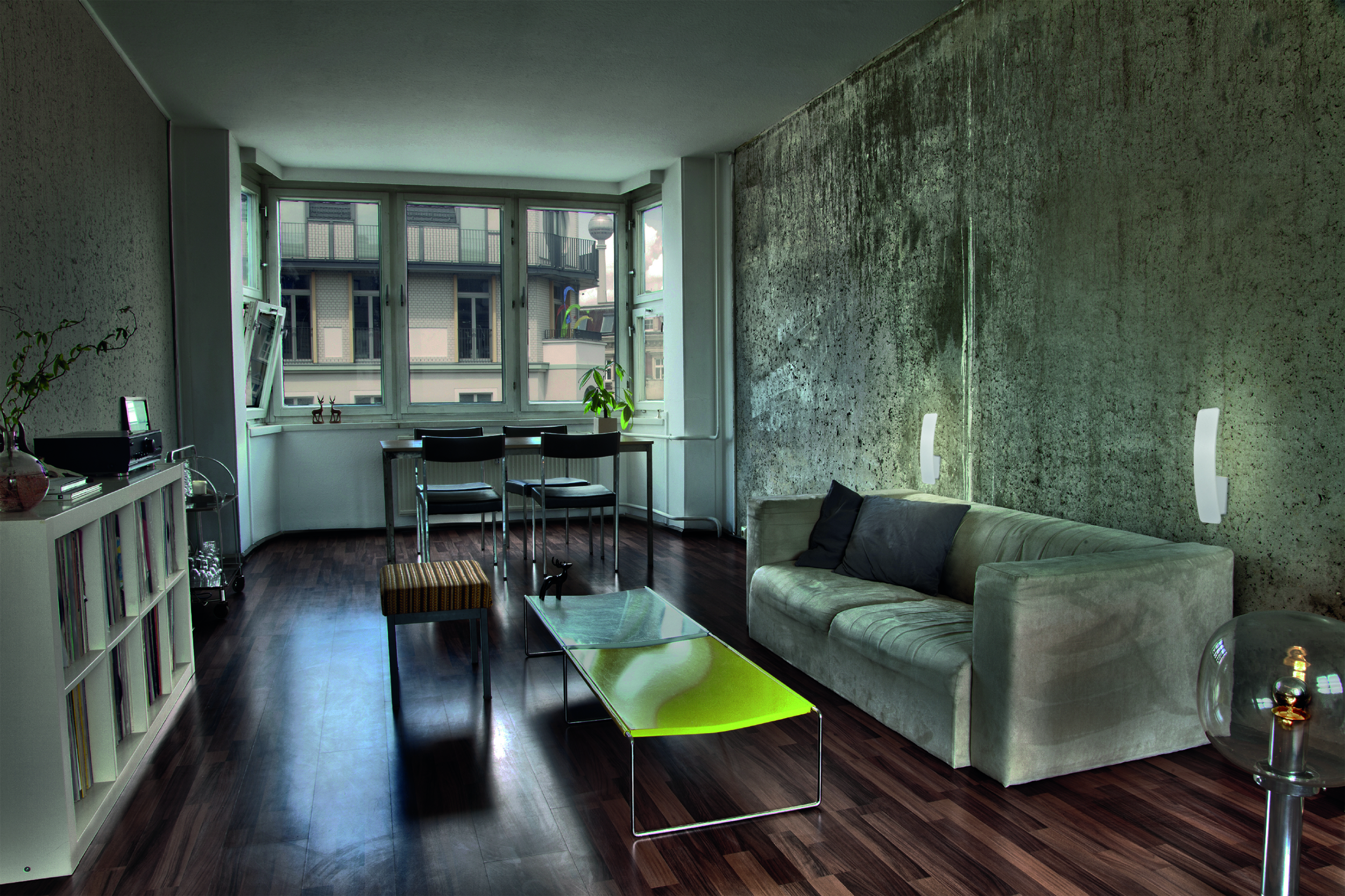 Ein Wohnzimmer mit Sofa, Couchtisch und großen Fenstern.