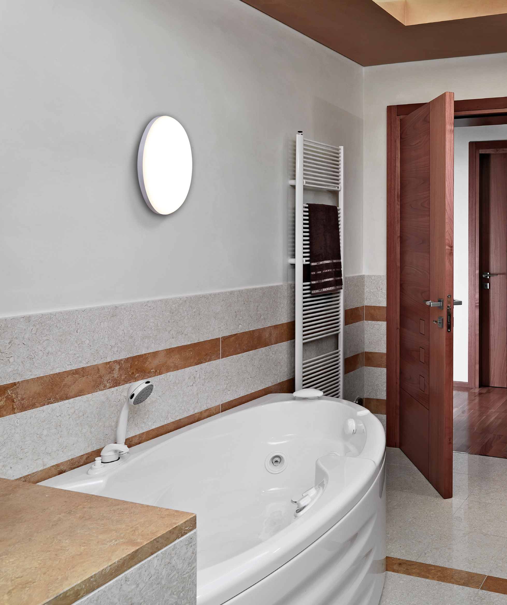 Ein weißes Badezimmer mit Badewanne, Wandleuchte und Handtuchhalter.