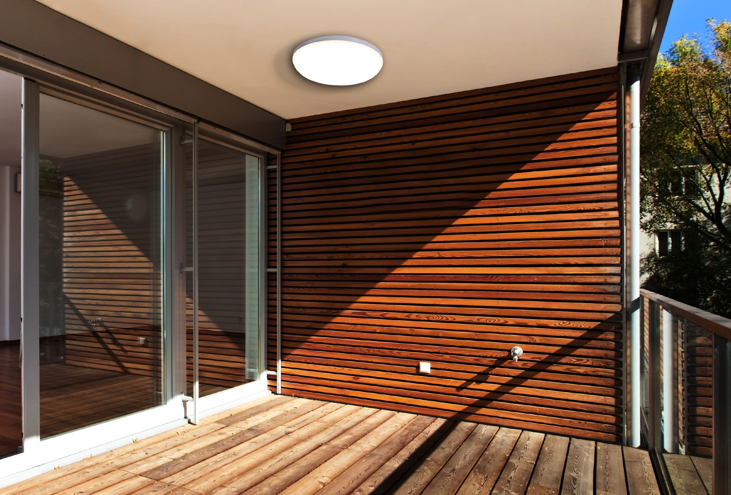 Holzbalkon mit hellem Deckenlicht und Blick auf Bäume.