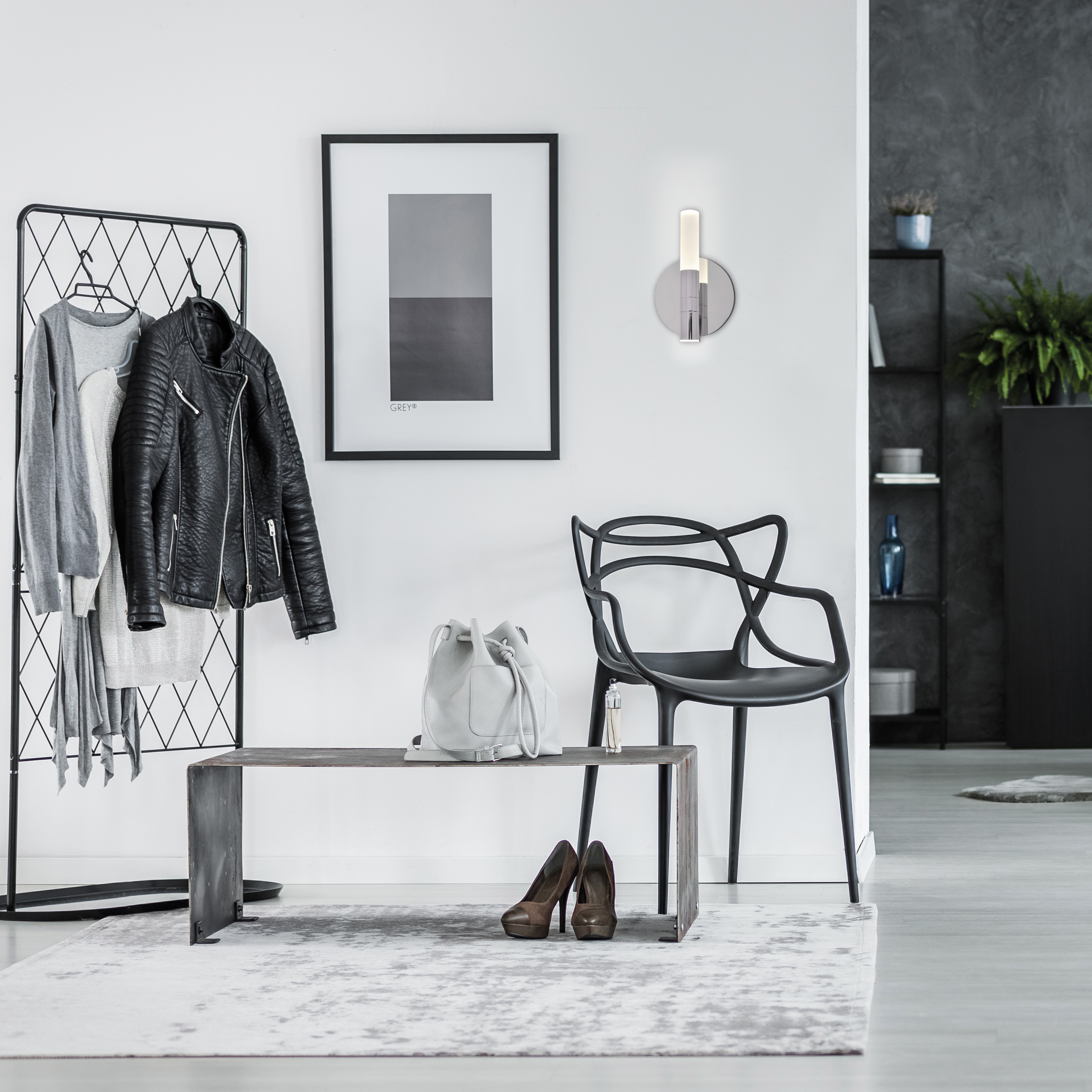 Flur mit schwarzem Stuhl, Sitzbank und gerahmtem Bild, neben einer Garderobe.