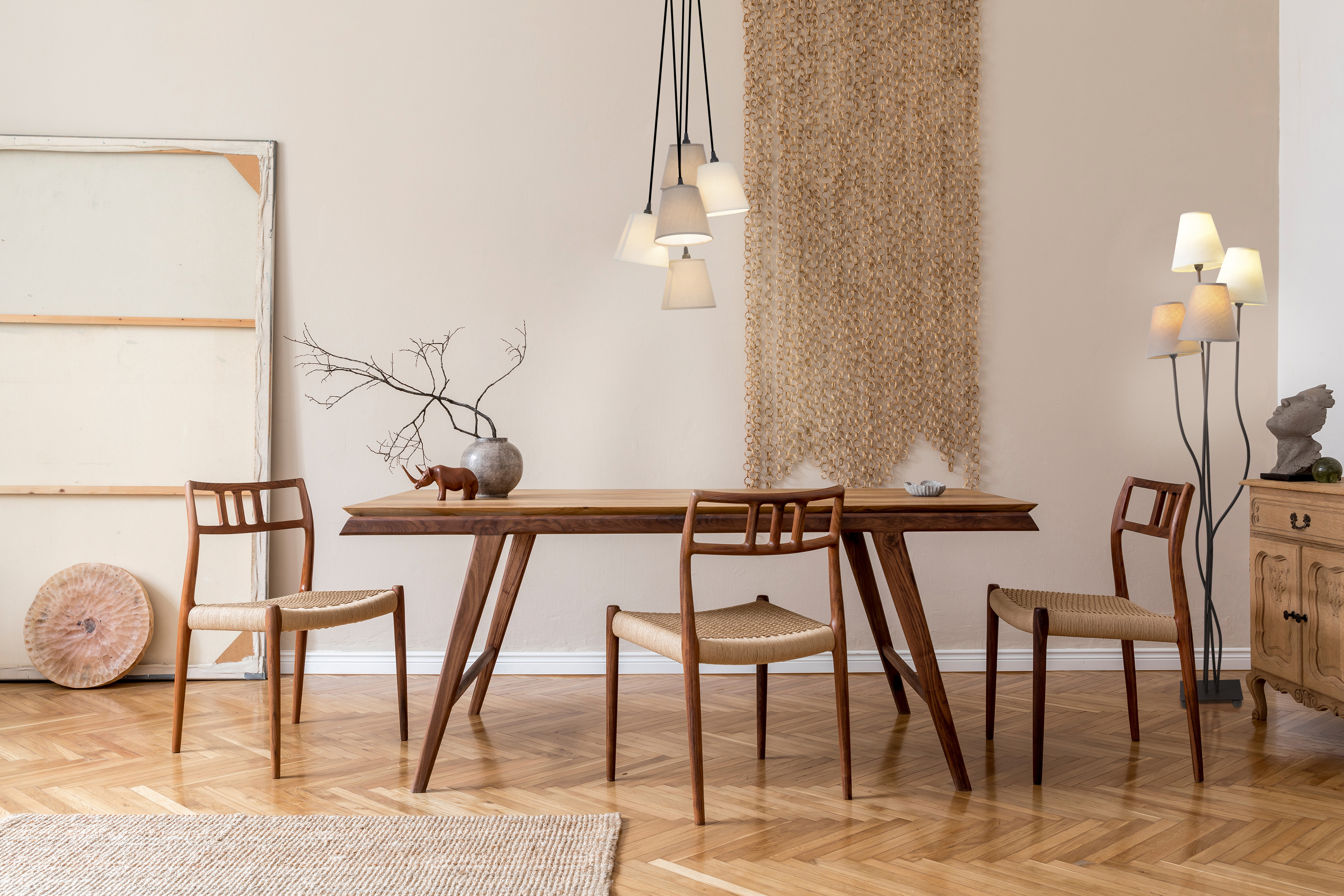 Esszimmer mit Holztisch, Stühlen und Pendelleuchte. Beige Wände und Wandbehang.