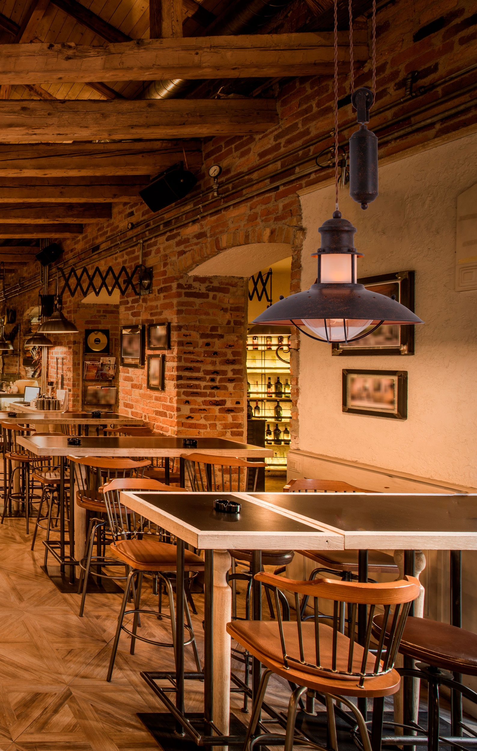 Innenraum eines Restaurants mit Tischen, Stühlen und Hängelampen.