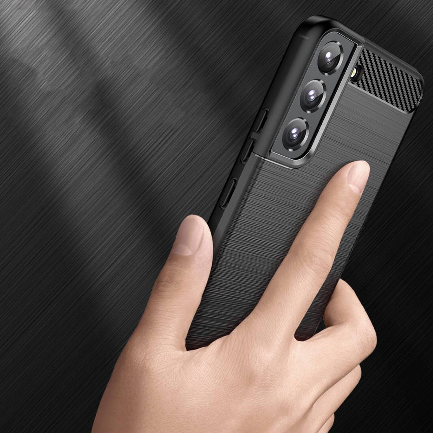 Eine Hand hält ein schwarzes Telefon mit drei Kameras, vor dunklem, strukturiertem Hintergrund.