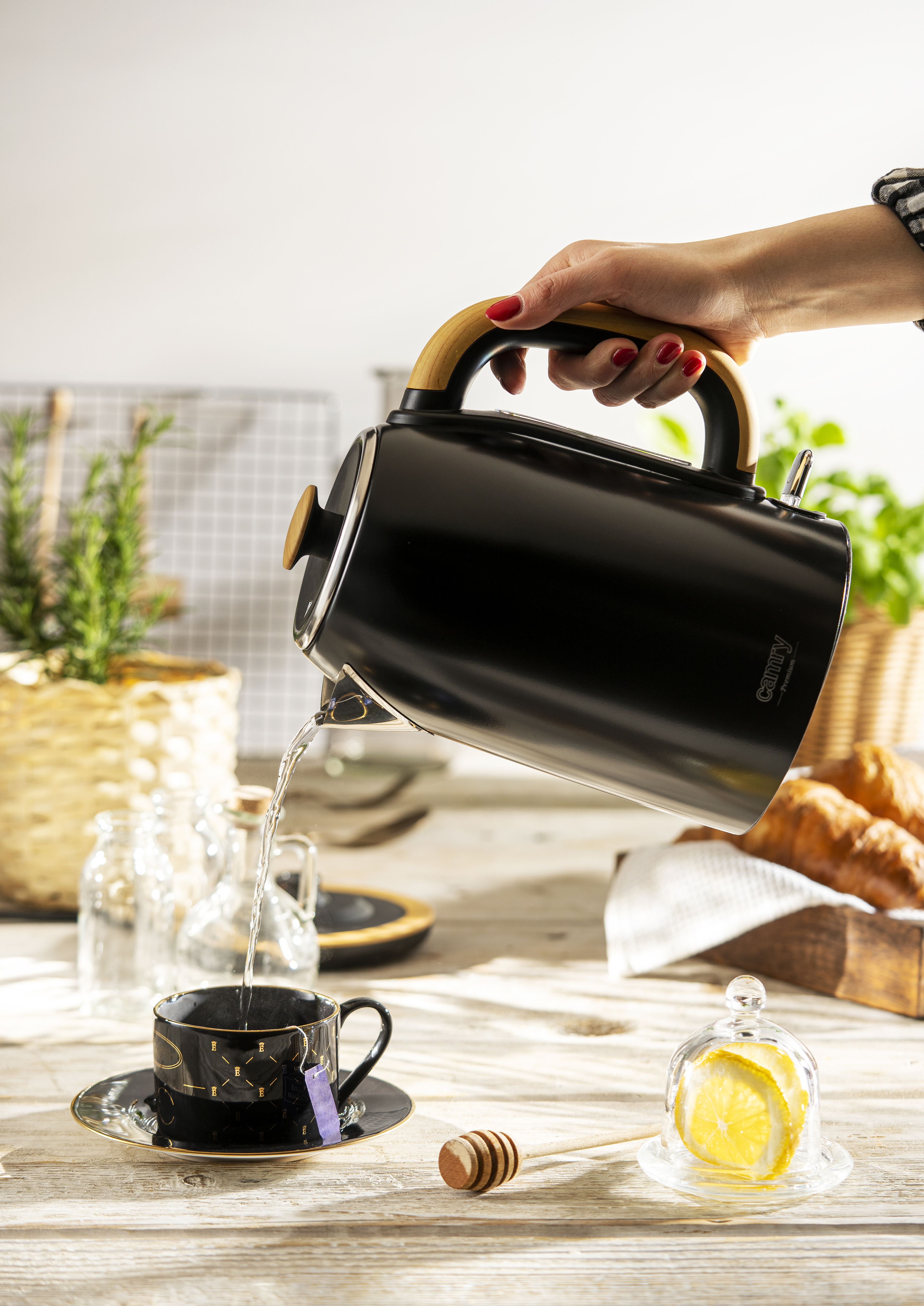 Femme versant de l'eau d'une bouilloire noire dans une tasse à thé.