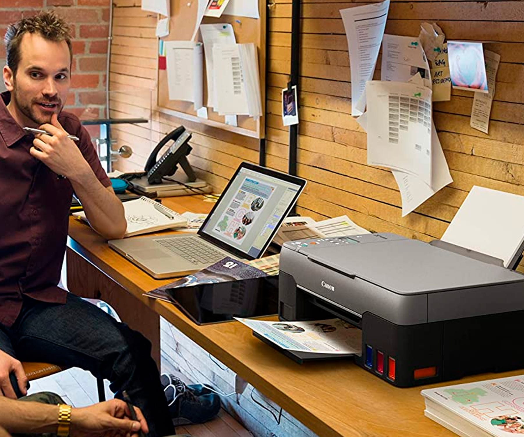 Mężczyzna i drukarka na biurku z papierami.