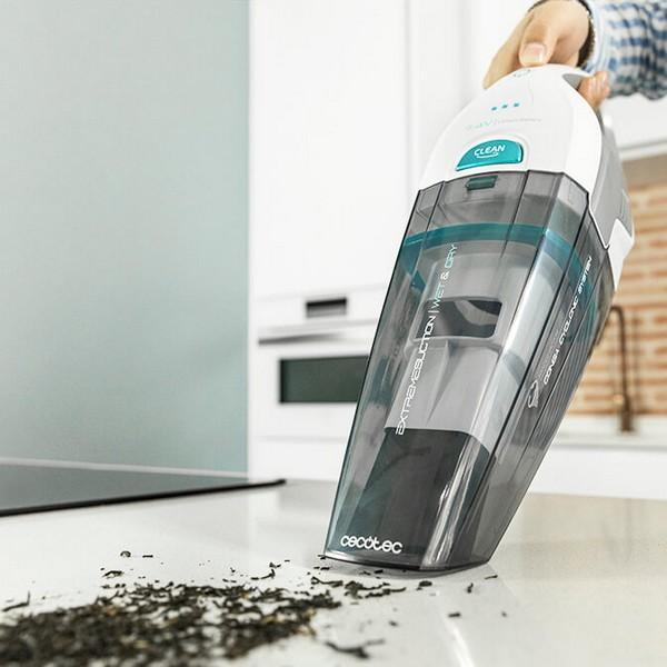 Aspirapolvere portatile, bianco e grigio, usato su un piano di lavoro bianco con foglie di tè.