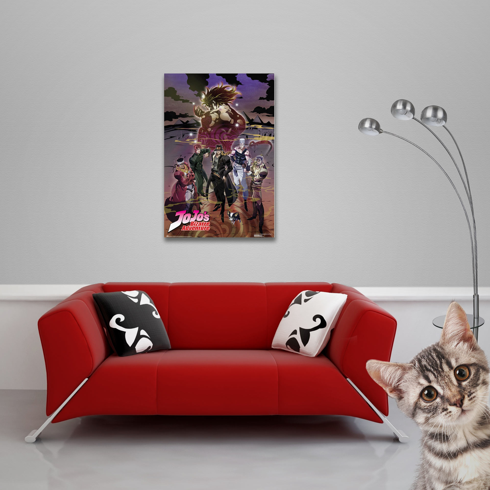 Rotes Sofa mit Kissen. Ein Poster an der Wand. Eine Katze, die in die Kamera schaut. Graue Wand und Boden.