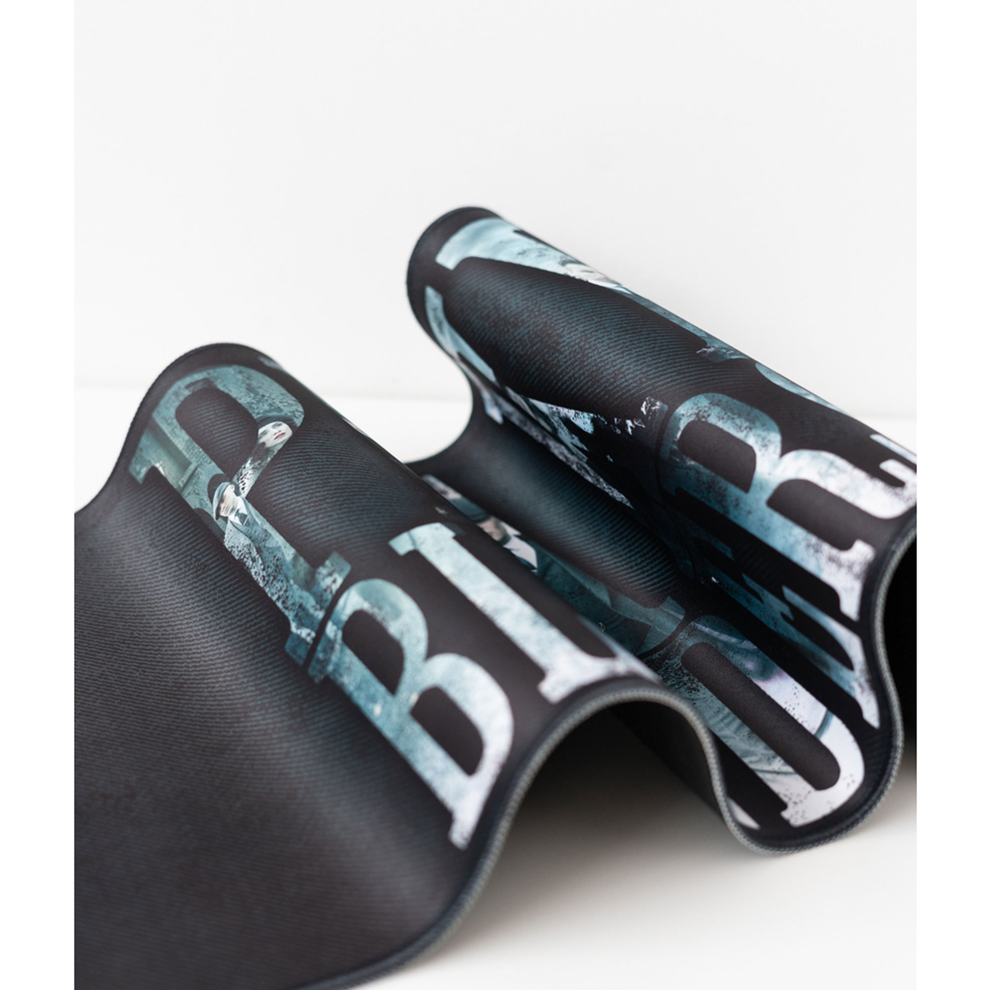 Ein schwarzes Mousepad mit weißem und blauem Design, aufgerollt. Der Hintergrund ist weiß.