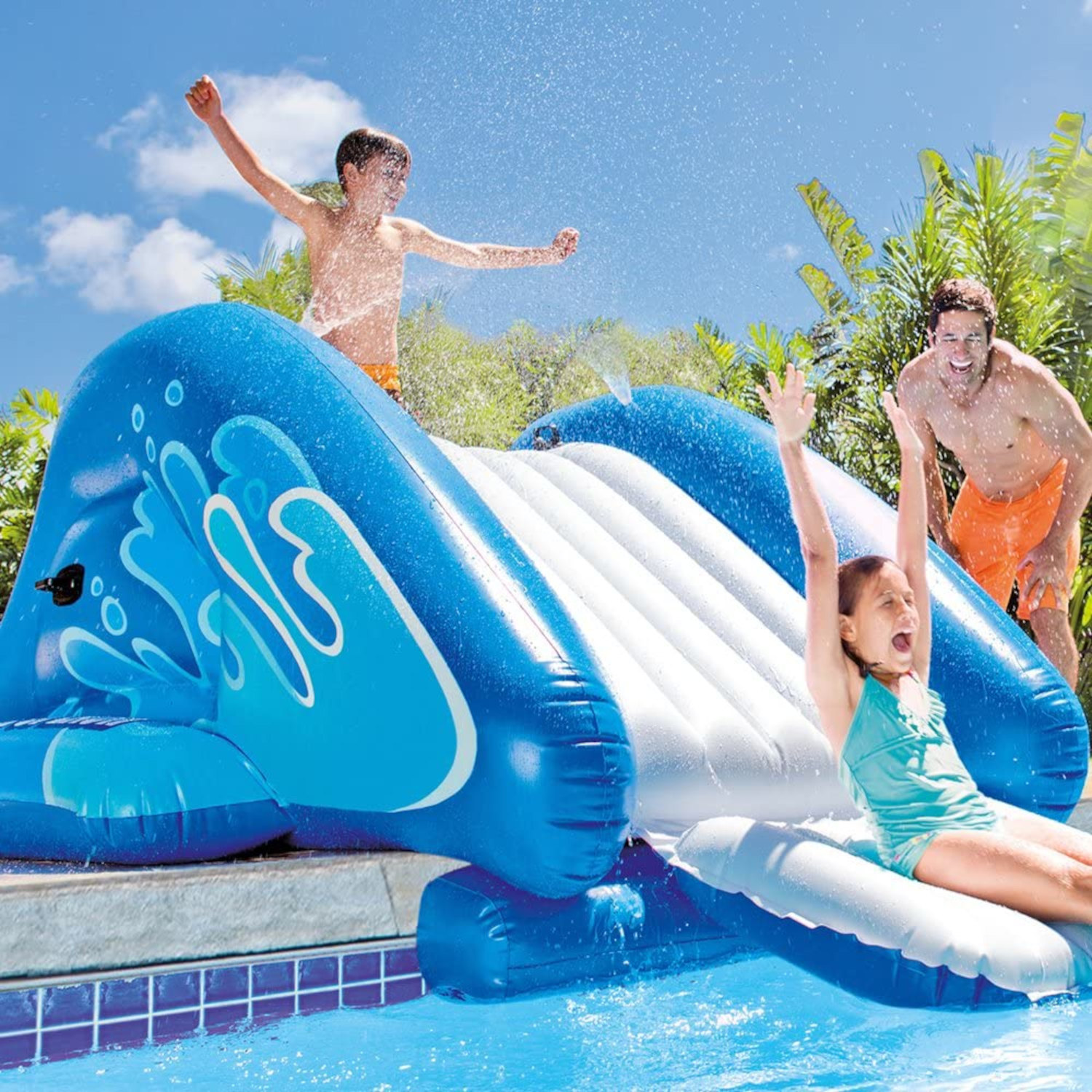 Kinder rutschen eine blaue aufblasbare Wasserrutsche in einen Pool hinunter, ein Mann in der Nähe.