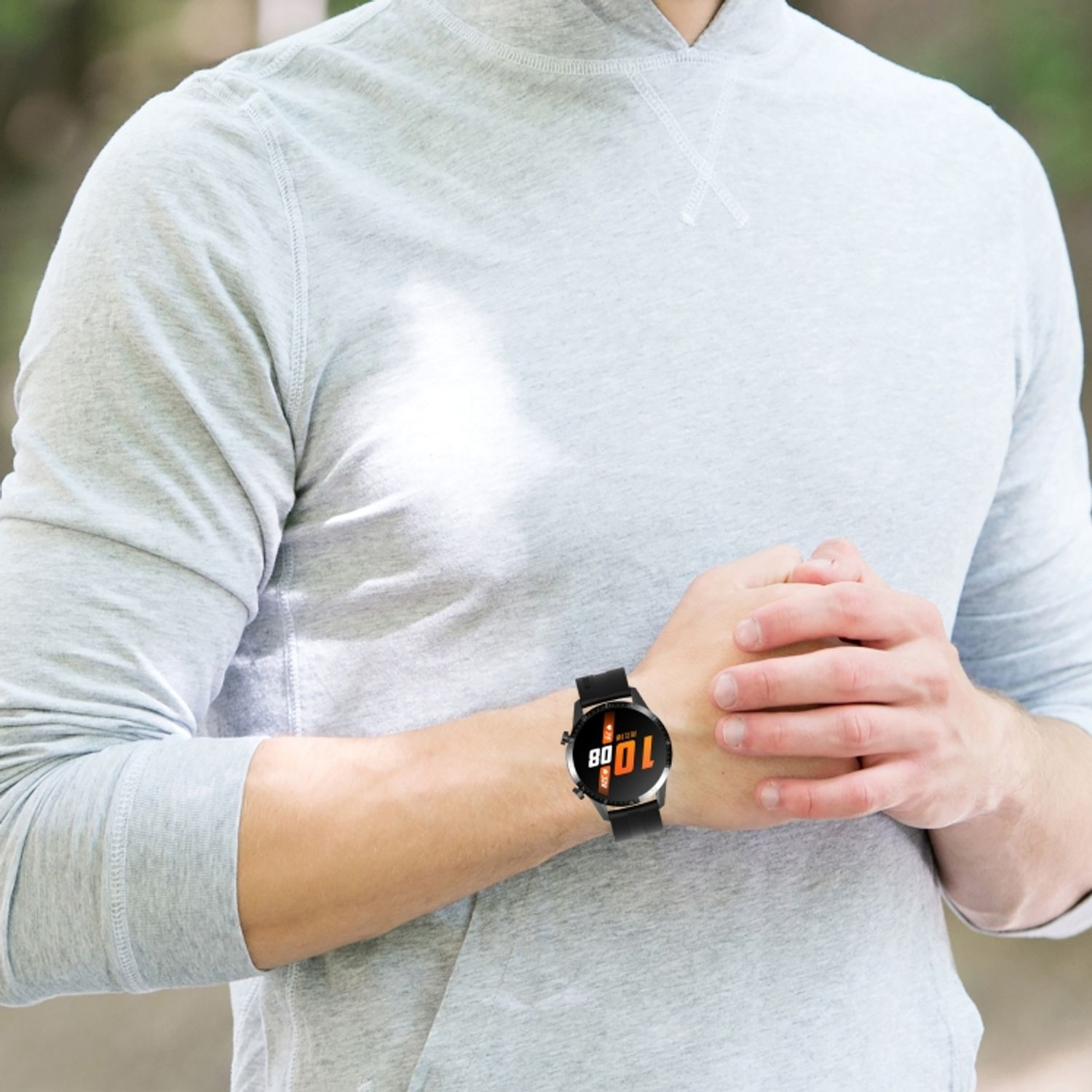 Ein Mann trägt eine Smartwatch. Die Uhr zeigt die Uhrzeit: 10:08. Er ist im Freien.