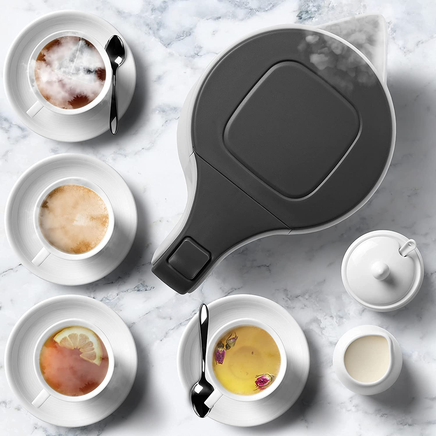 Draufsicht auf einen Wasserkocher mit Kaffee- und Teetassen. Dampf und Sahne.
