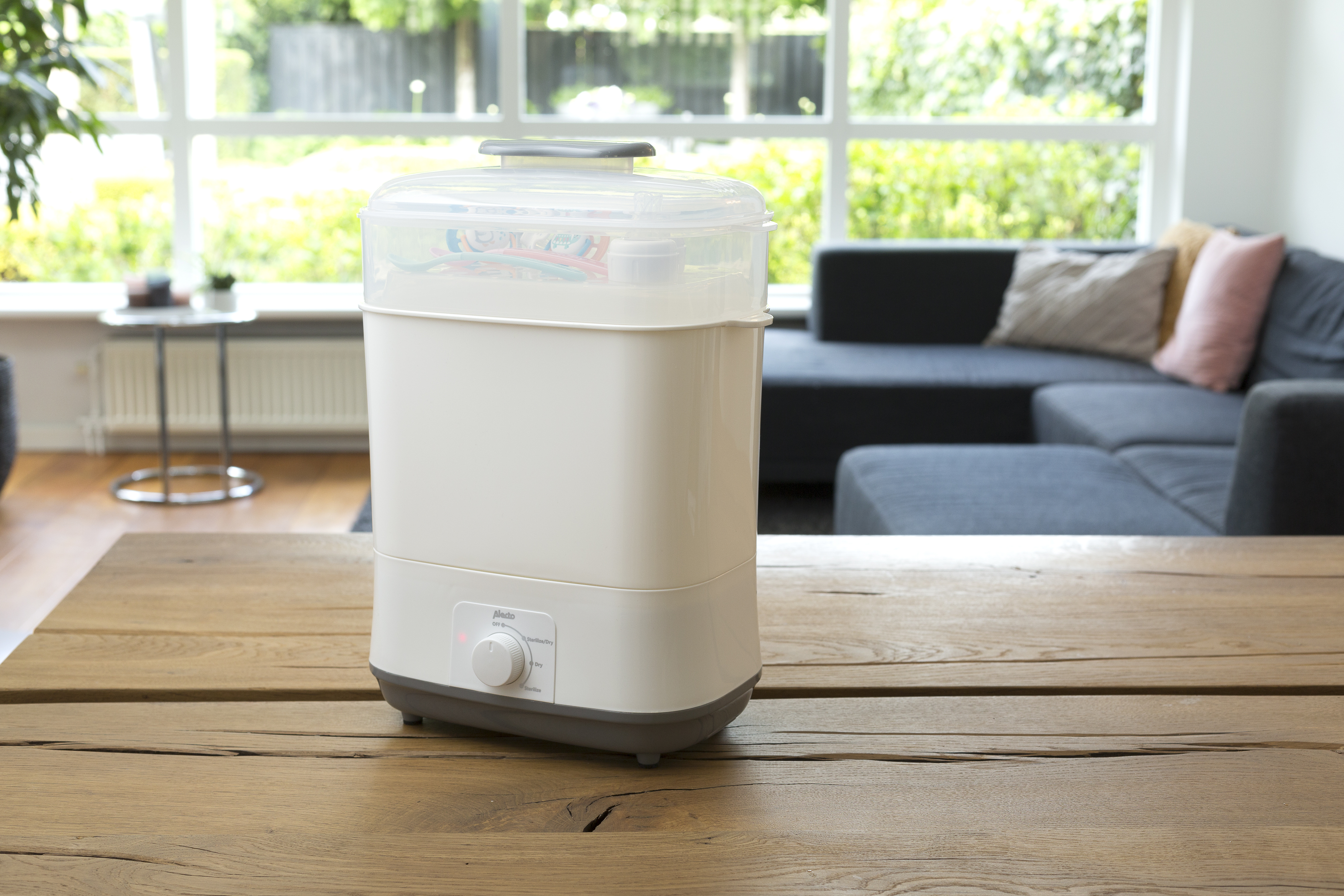 Baby bottle sterilizer on a wooden table in front of a window.