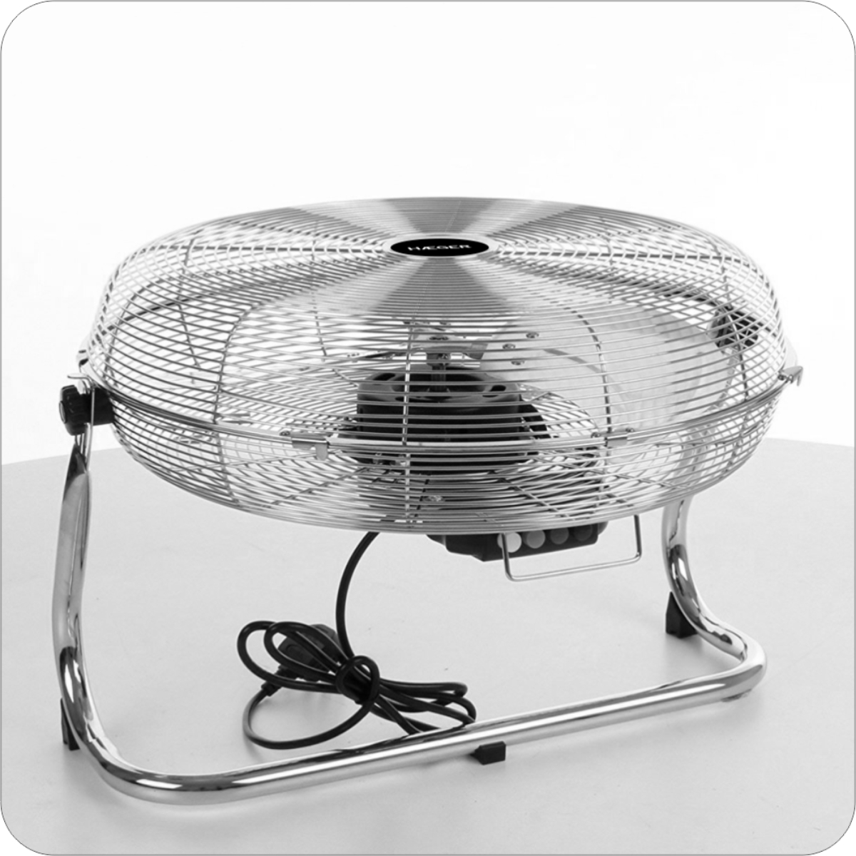 Un ventilatore rotondo argentato su un tavolo con un cavo nero.
