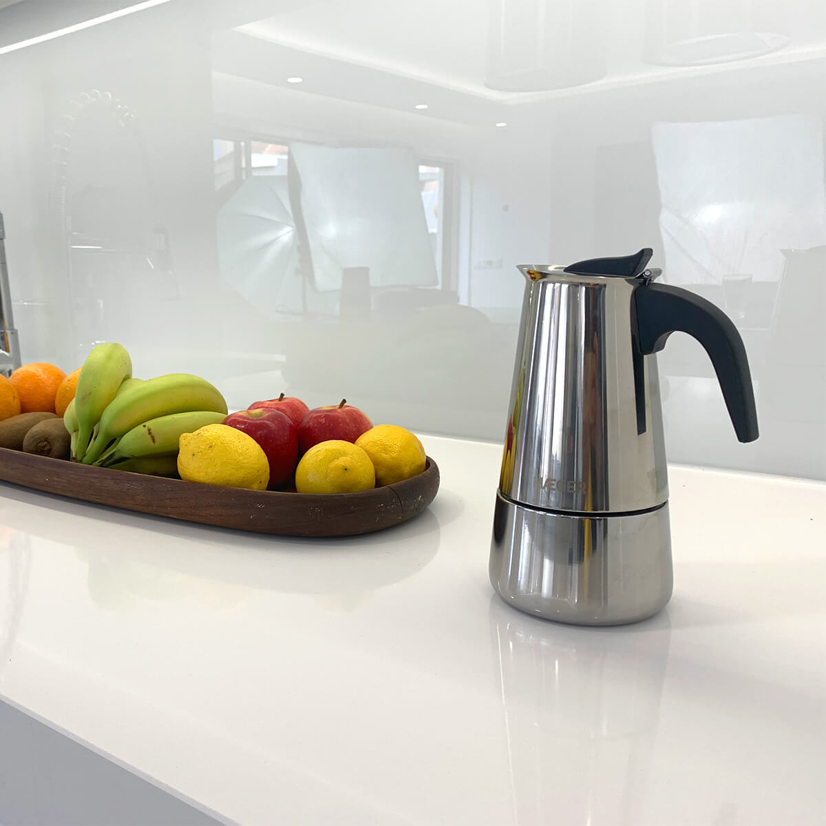 Ekspres do kawy ze stali nierdzewnej z tacą owoców: banany, cytryny, jabłka i kiwi.