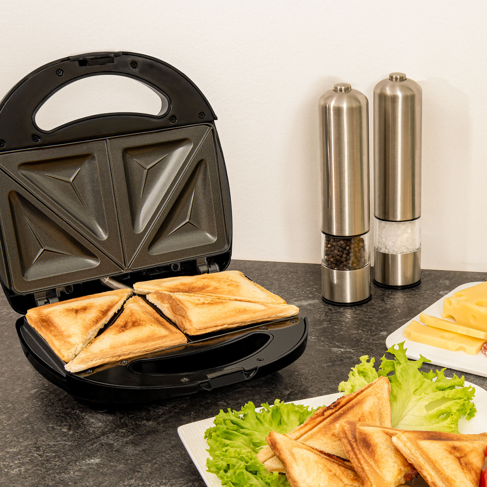 Sandwichmaker mit getoasteten Sandwiches, Käse und Salz- und Pfefferstreuern.