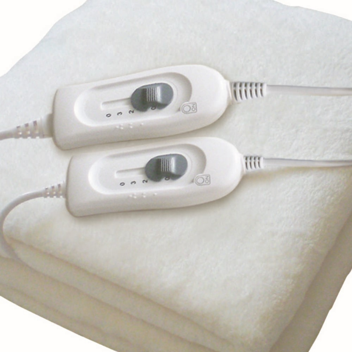 Zbliżenie białego koca elektrycznego z dwoma oddzielnymi kontrolerami. Każdy kontroler ma pokrętło i przewód.