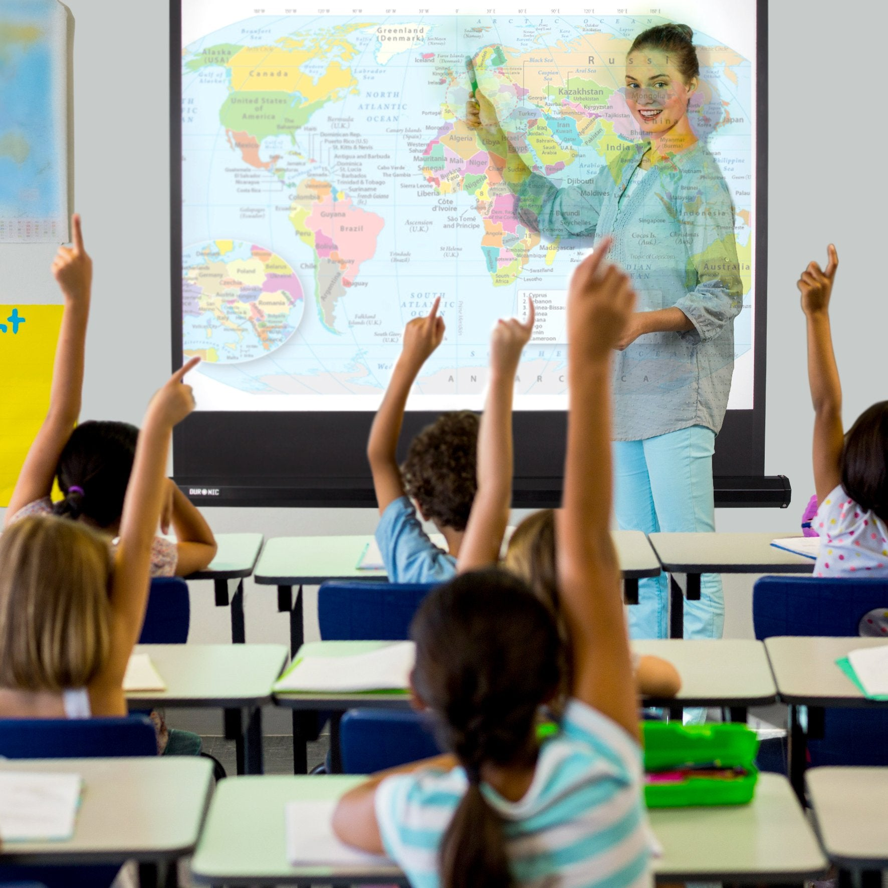Eine Lehrerin zeigt auf eine Weltkarte auf einer Leinwand, Schüler heben die Hände in einem Klassenzimmer.