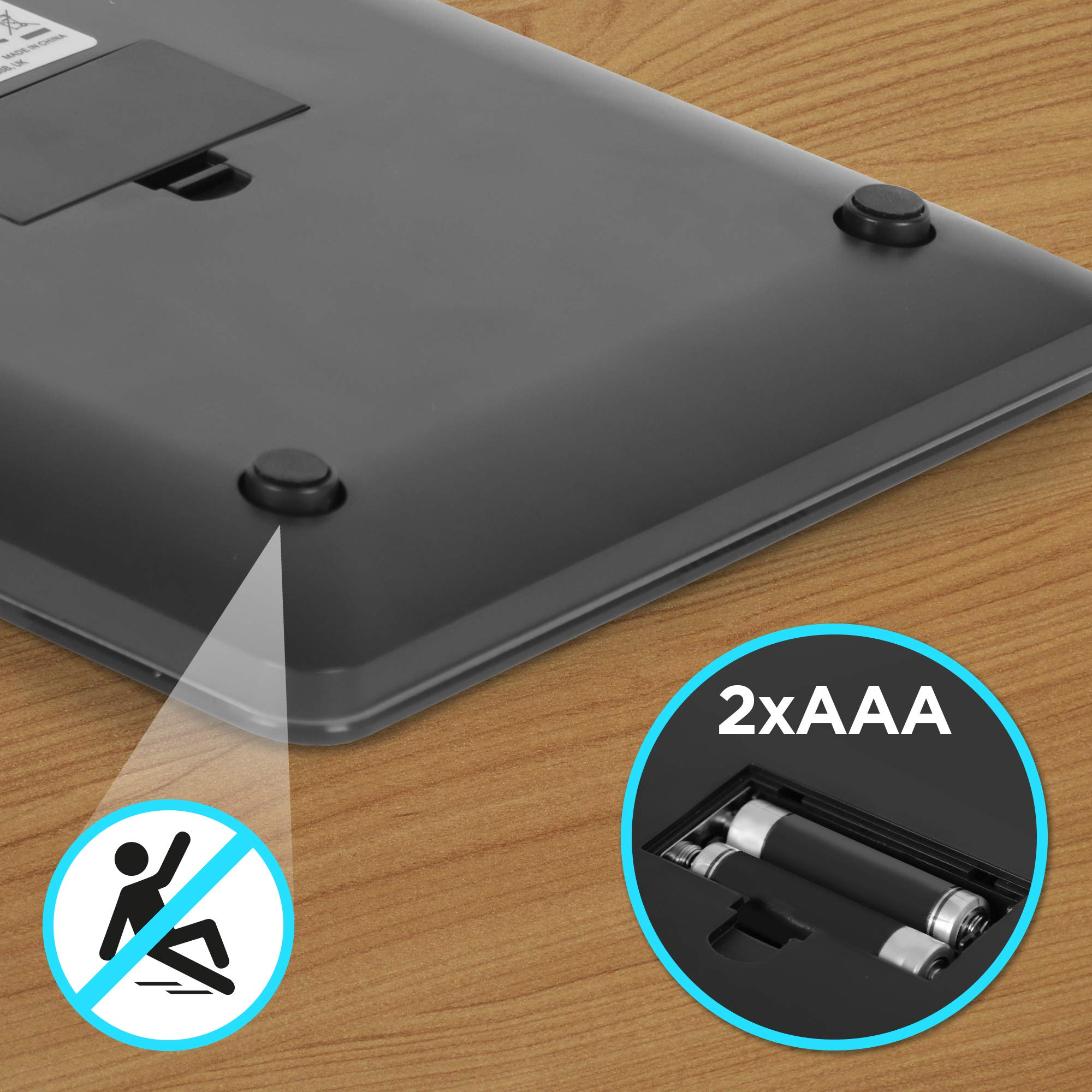 Nahaufnahme einer schwarzen Waagenbasis mit Batterien und einem Warnsymbol.