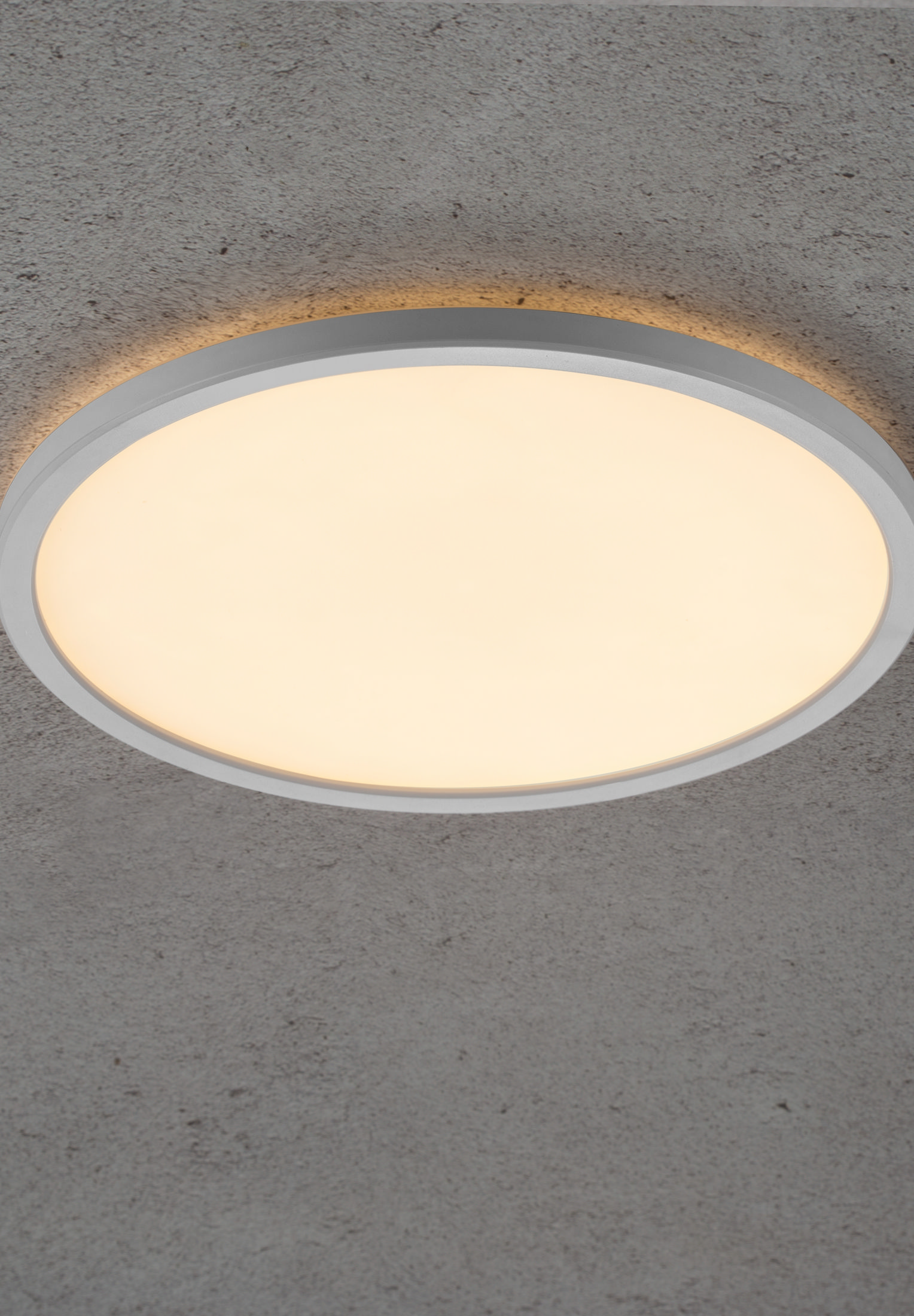 Eine runde Deckenleuchte ist eingeschaltet. Das Licht ist weiß mit einem grauen und Betonhintergrund.