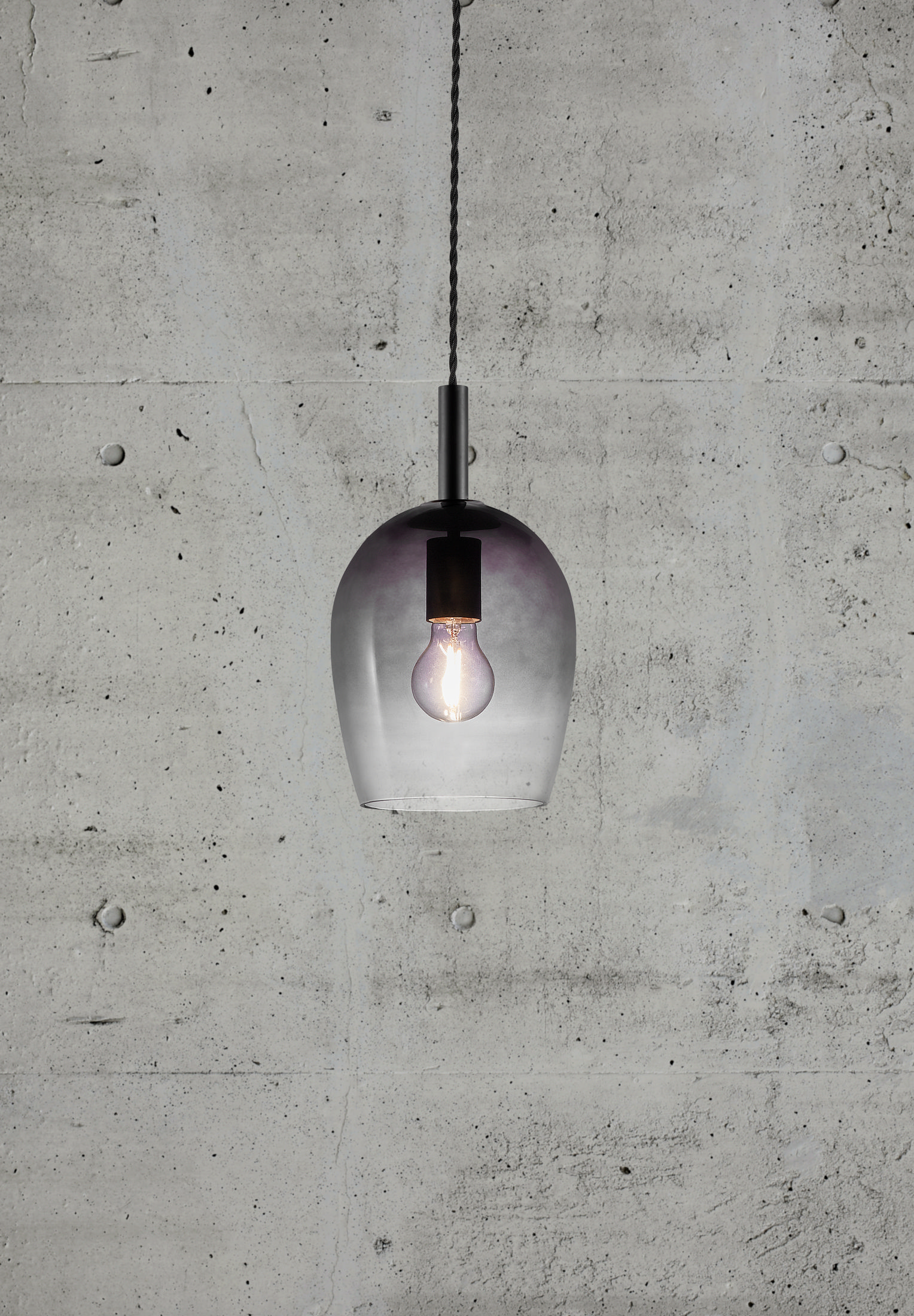 Hängeleuchte mit Farbverlauf-Glasschirm und Glühbirne, vor einer Betonwand.