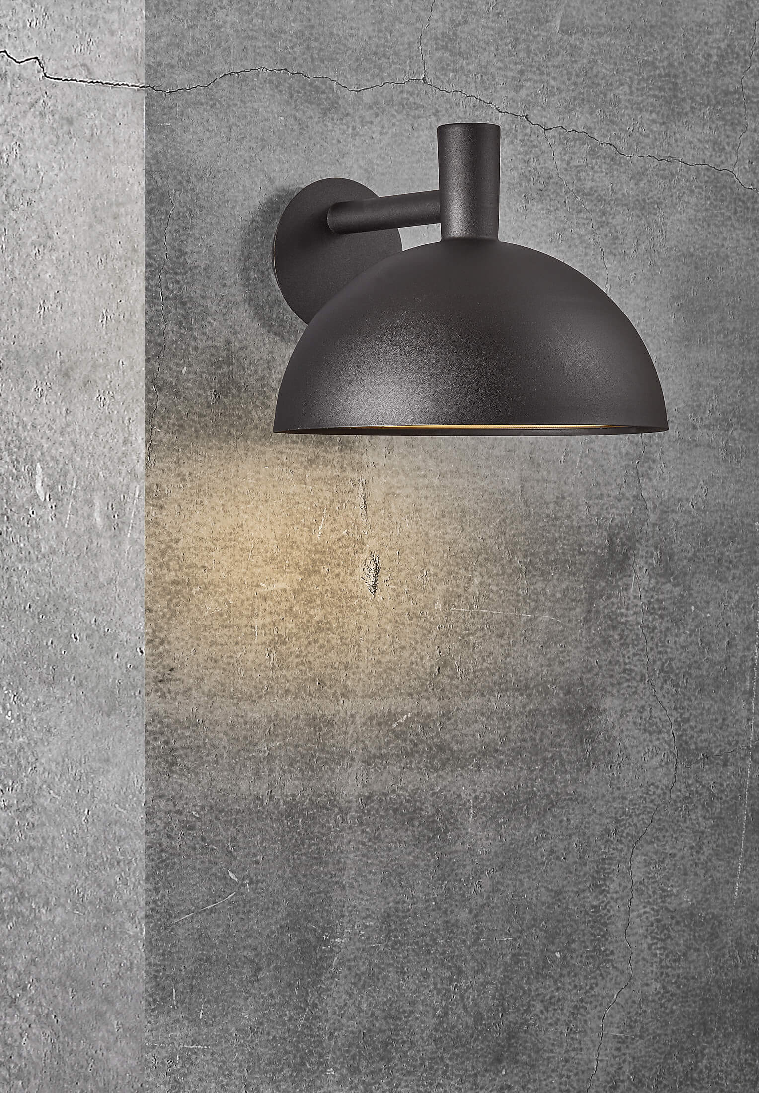 Schwarze Außenwandleuchte an einer strukturierten grauen Wand. Das Licht scheint nach unten.