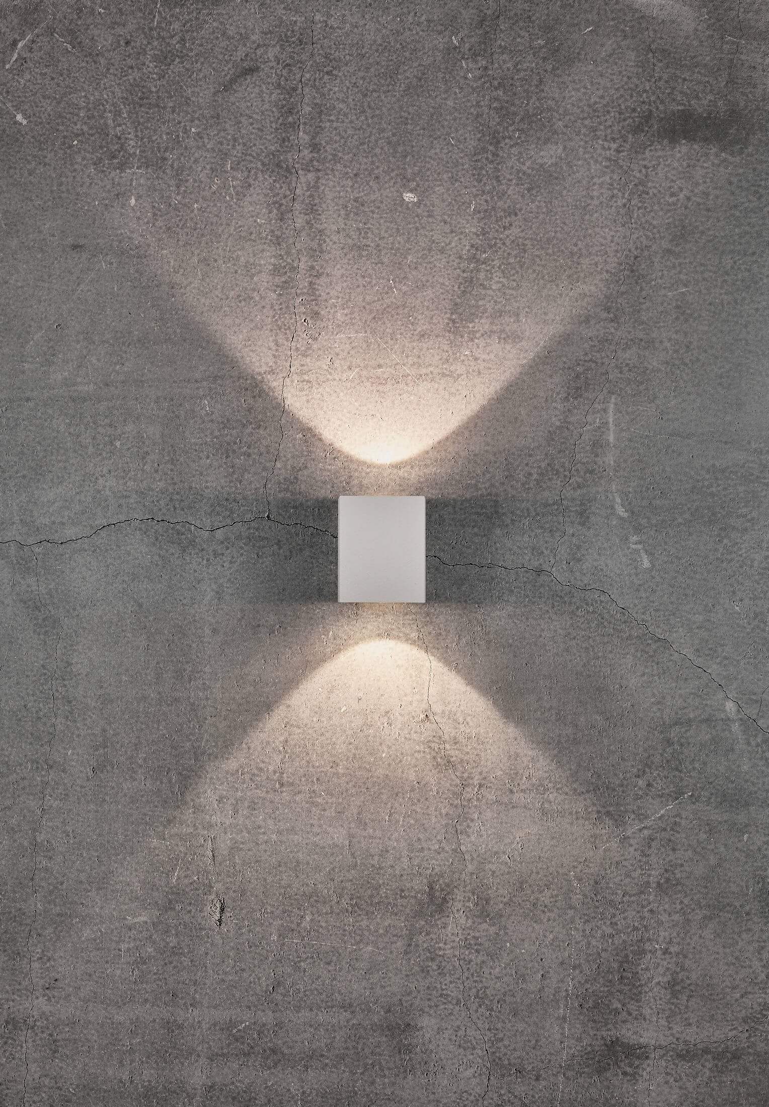 Eine weiße Wandleuchte, die Licht nach oben und unten auf eine strukturierte graue Wand abstrahlt.