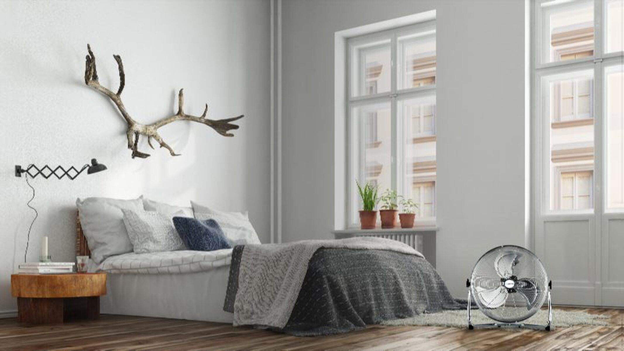 Dormitorio con cama, ventilador y pared con cornamenta, ventana con plantas.