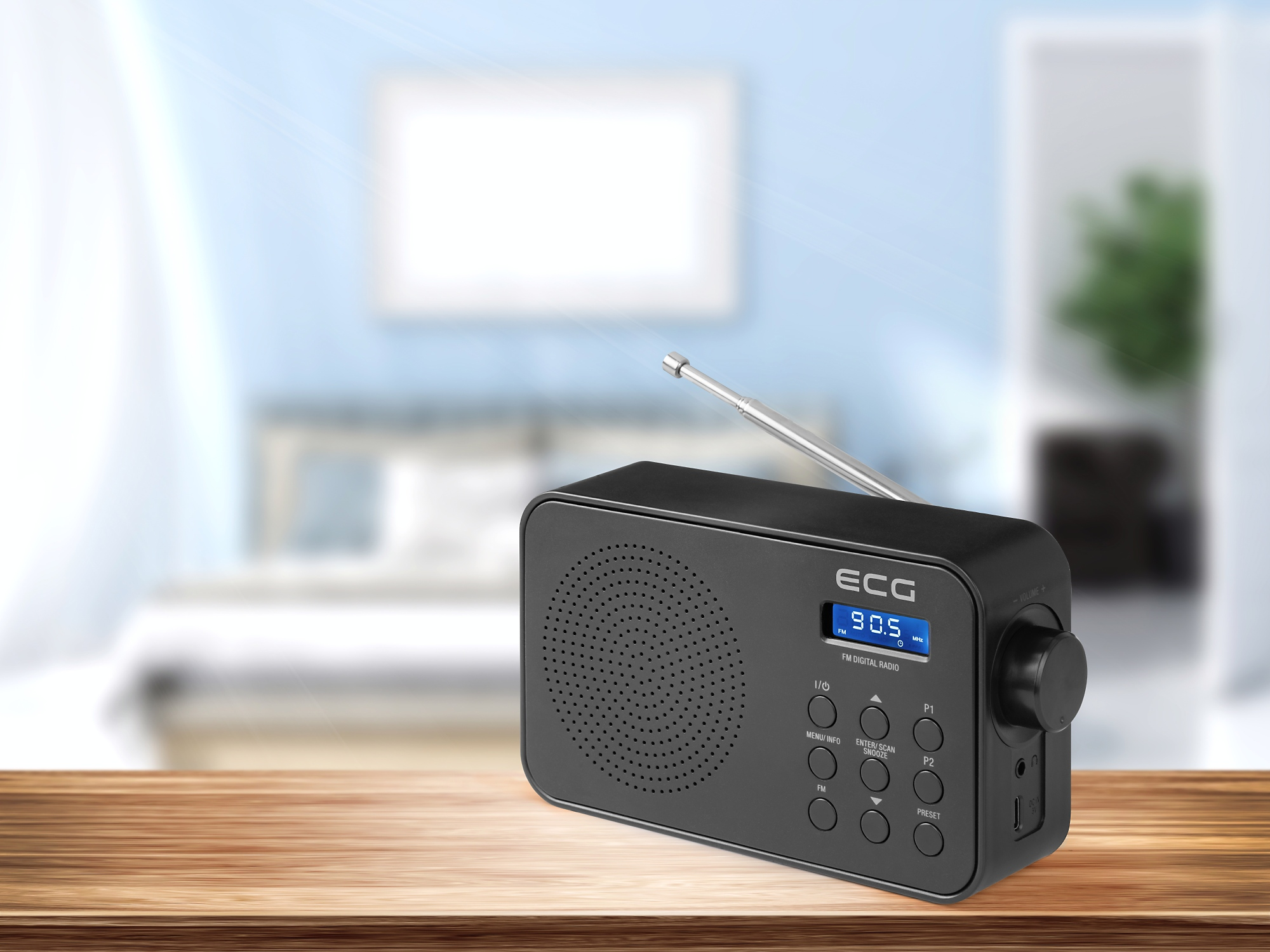 Schwarzes ECG Digitalradio auf einem Holztisch. Verschwommener Schlafzimmerhintergrund.