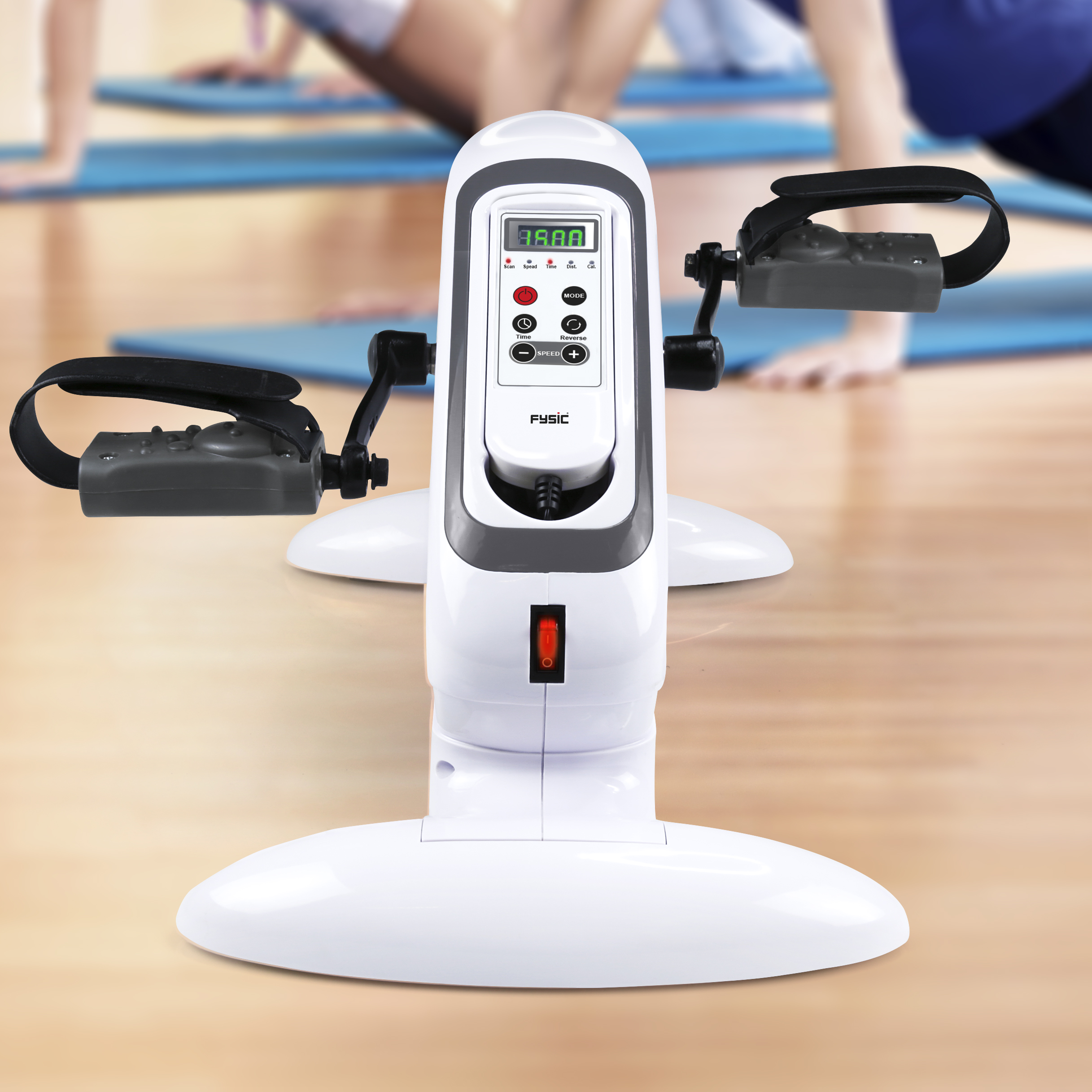 Witte hometrainer met een digitaal display en voetpedalen, in een kamer met yogamatten.
