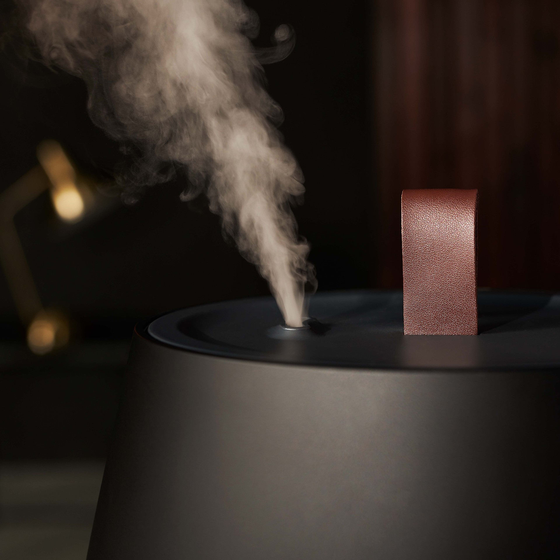 Czarny i szary nawilżacz uwalniający parę. Z boku znajduje się brązowy uchwyt.