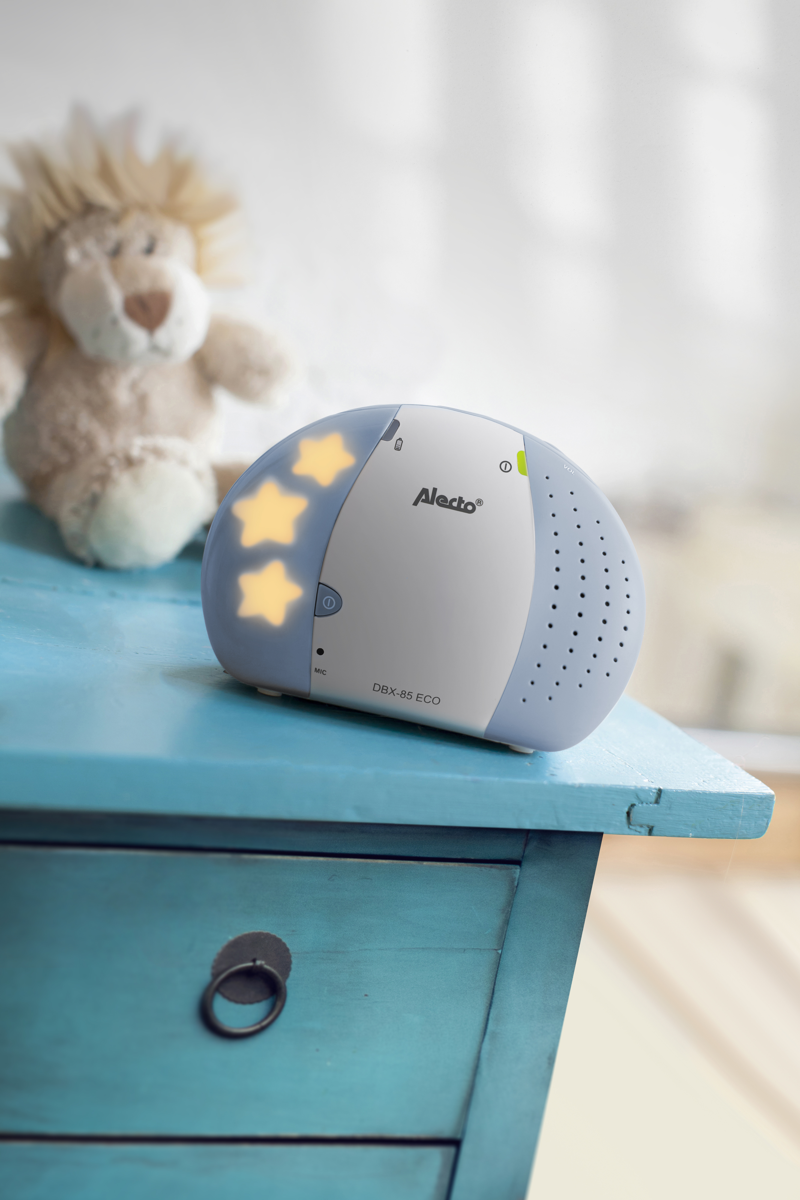 Un monitor para bebés en una cómoda azul. Un león de peluche está en el fondo.