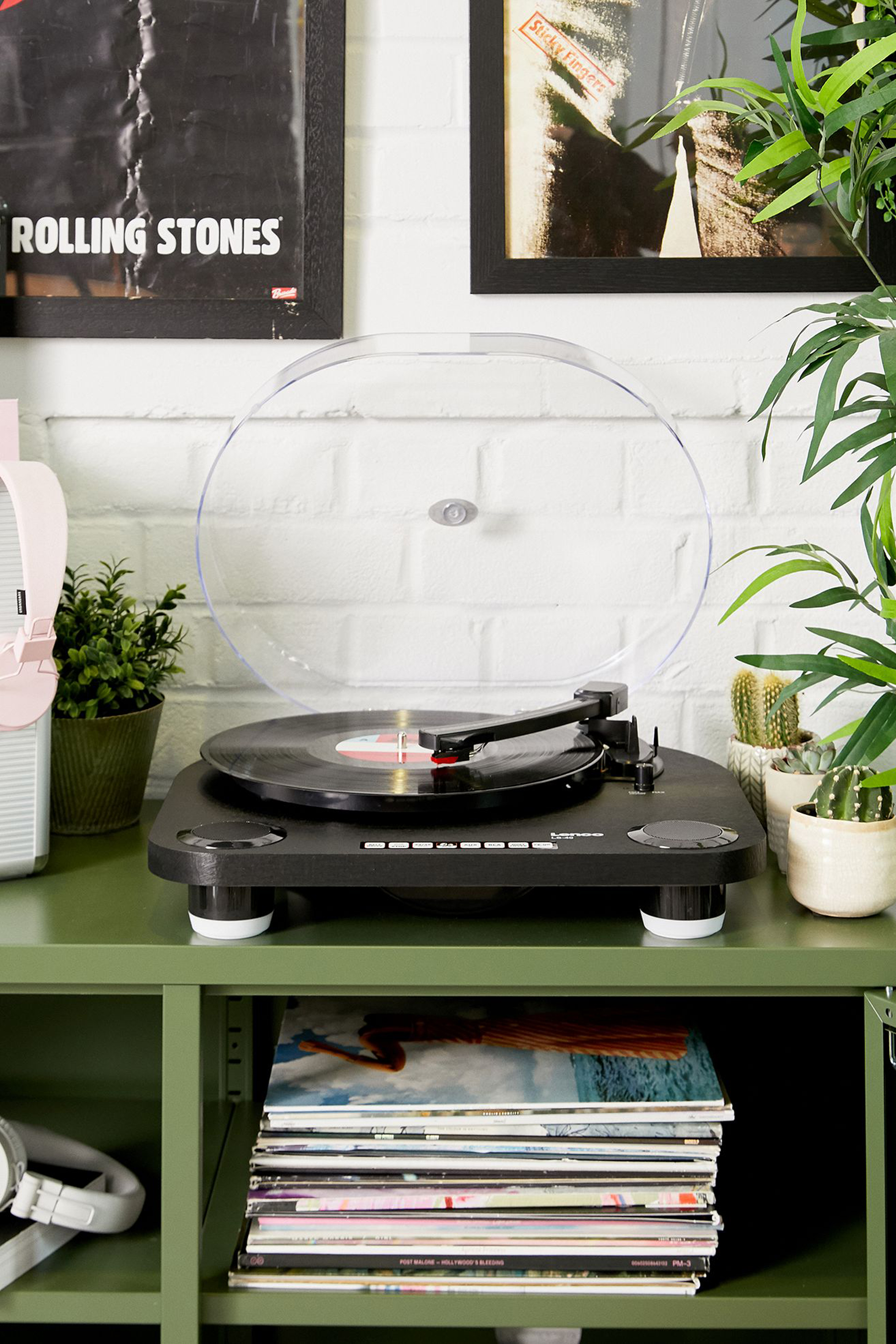 Platine vinyle avec couvercle transparent, disques et étagère verte.