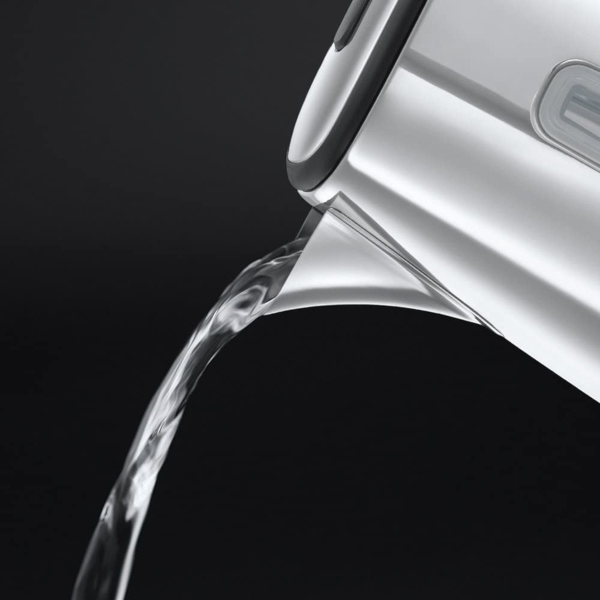 Acqua limpida versata da un bollitore d'argento su uno sfondo nero.