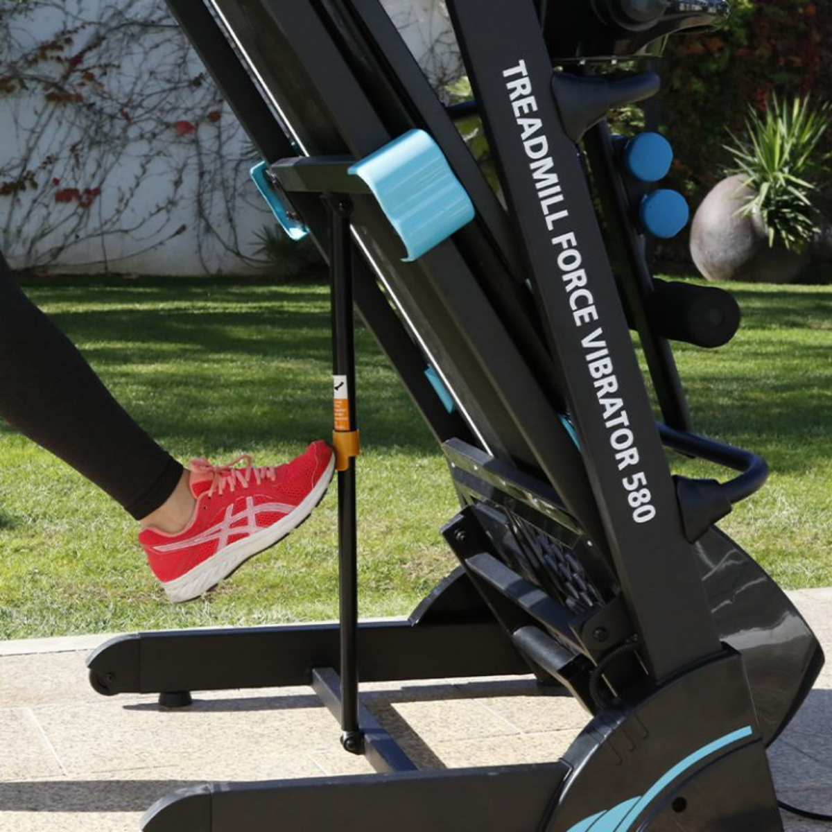 Persona usando cinta de correr, zapatos rojos, Treadmill Force Vibrator 580 visible.