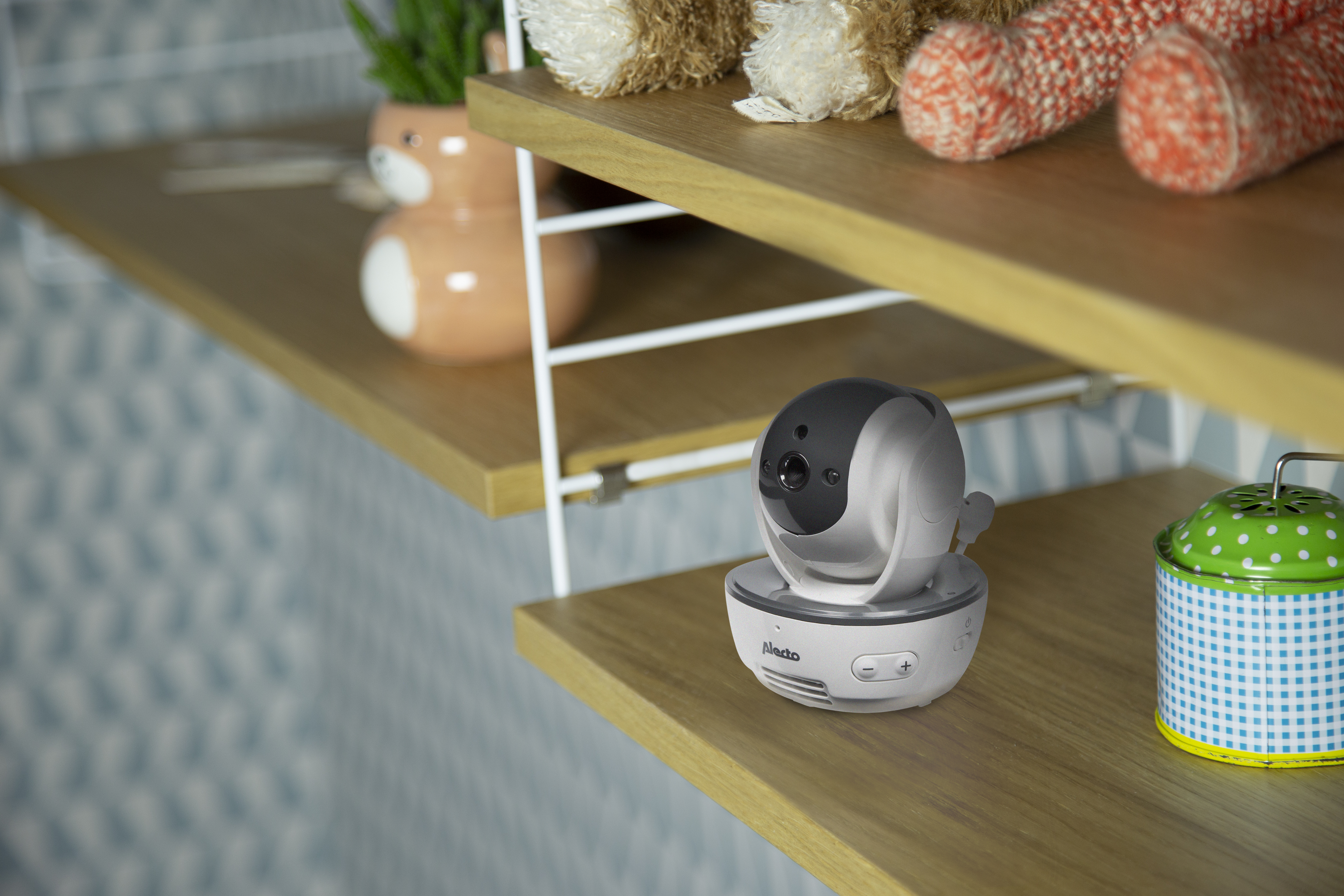 Babyphone-Kamera auf einem Regal mit Spielzeug und einem grünen Behälter.
