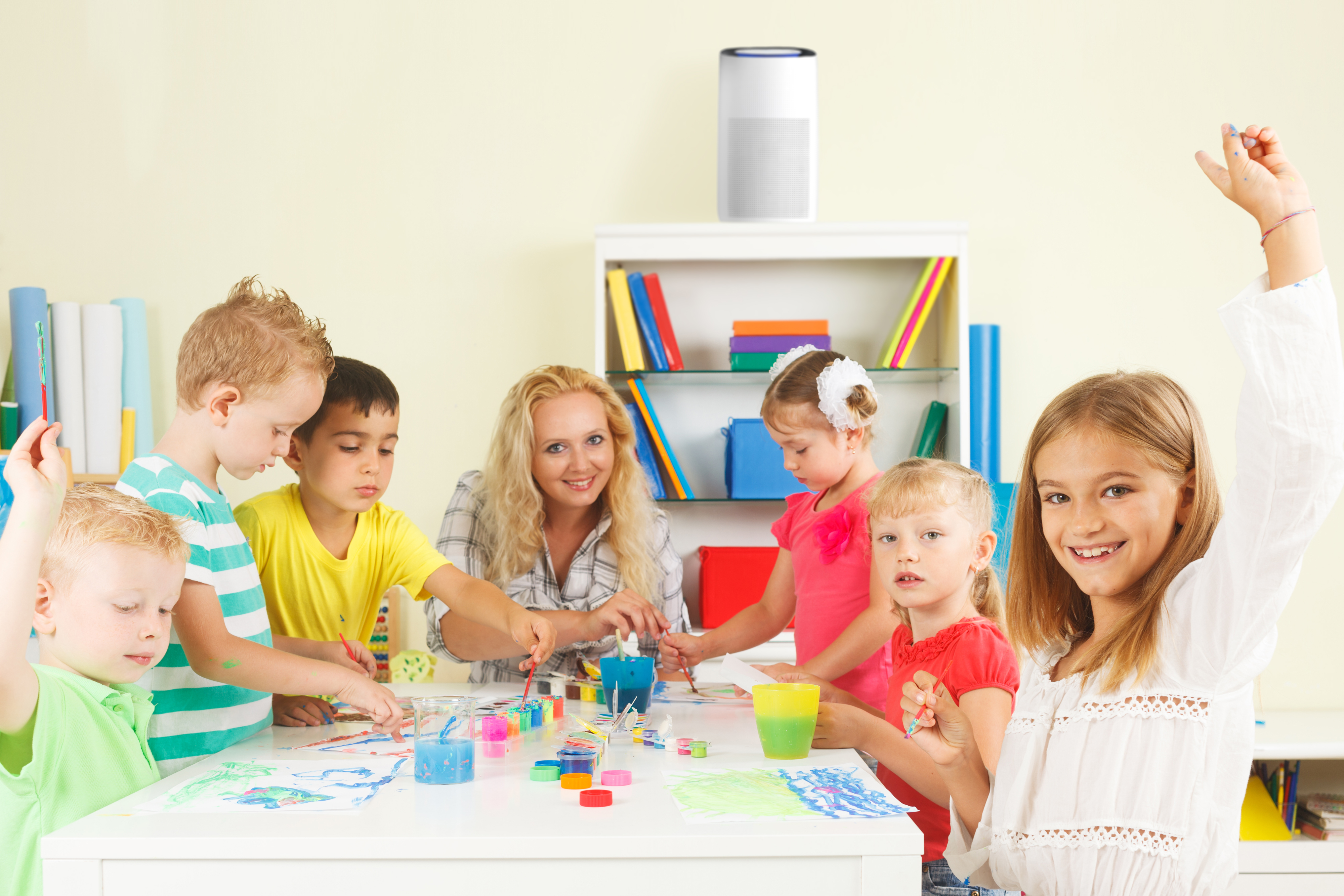 Gruppe von Kindern und eine Lehrerin, die an einem Tisch malen.