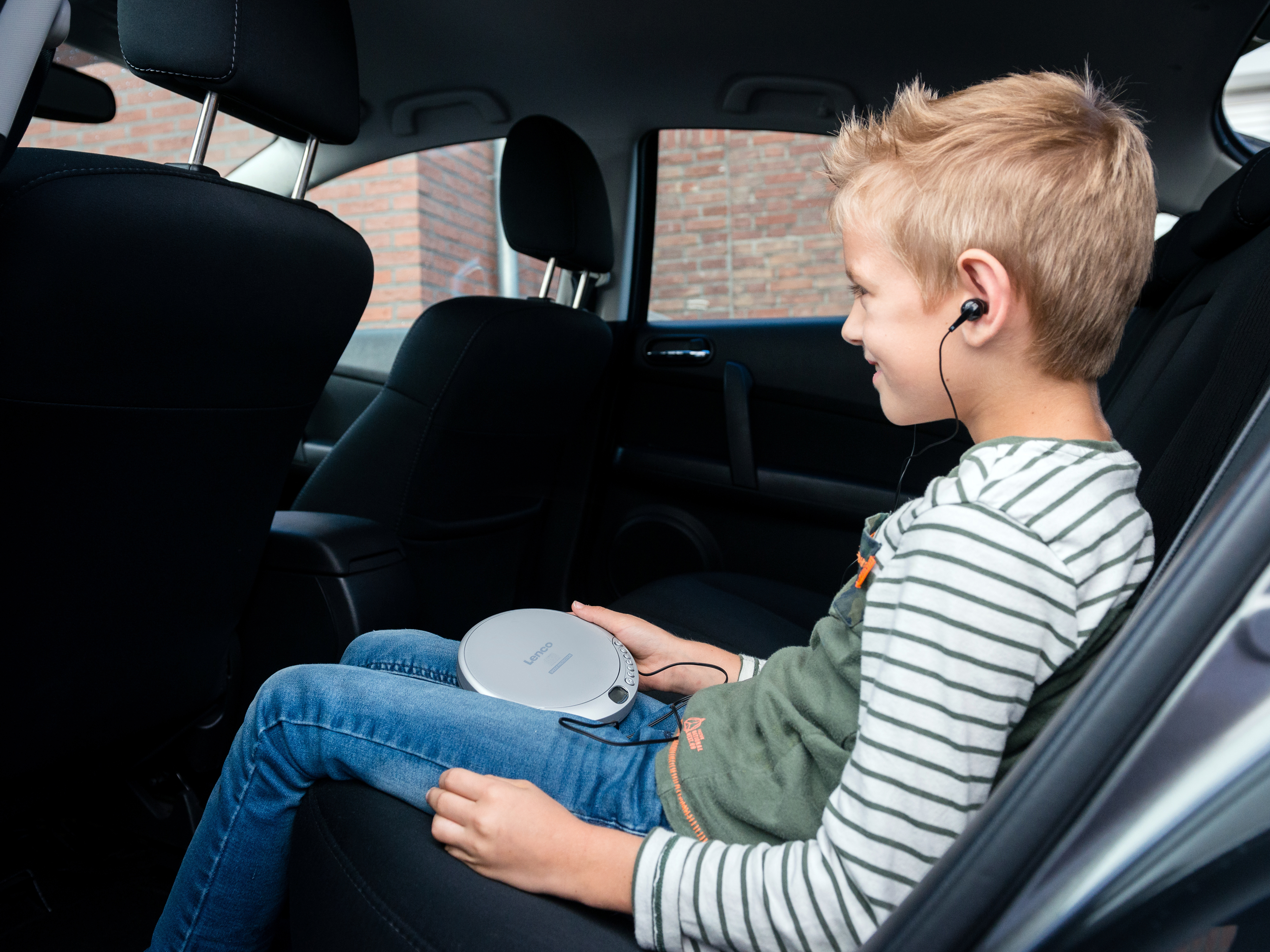 Chłopiec w samochodzie słucha muzyki z przenośnego odtwarzacza CD ze słuchawkami.