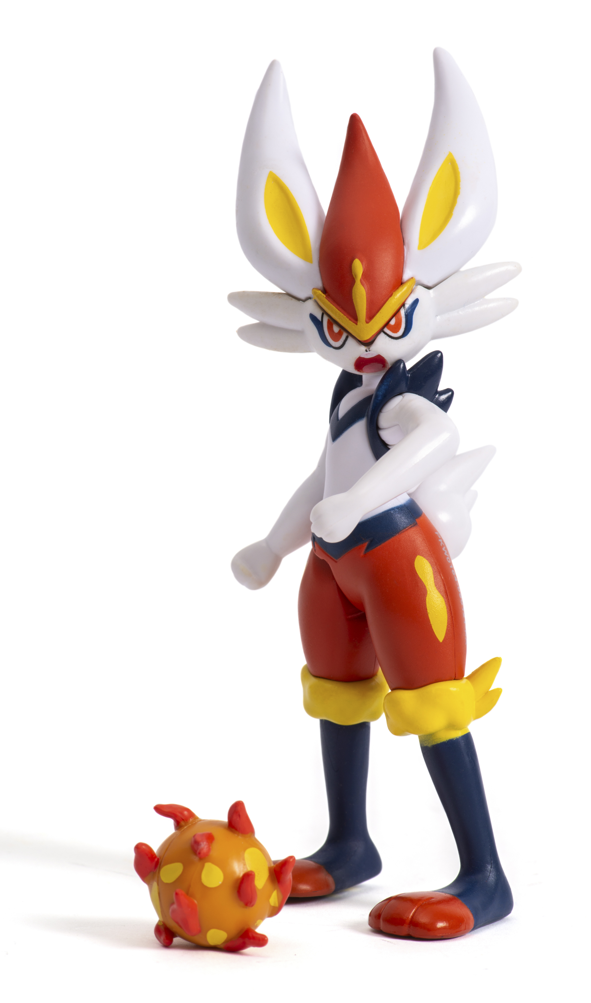 Eine Pokémon-Figur von Cinderace, rot, weiß und gelb, mit einem orangefarbenen Ball zu Füßen.