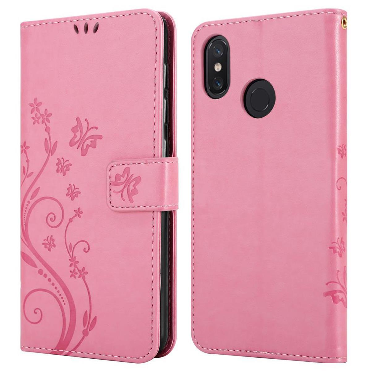 Custodia rosa per telefono, aperta e chiusa. Presenta un design a farfalle e fiori. Ha una chiusura magnetica.