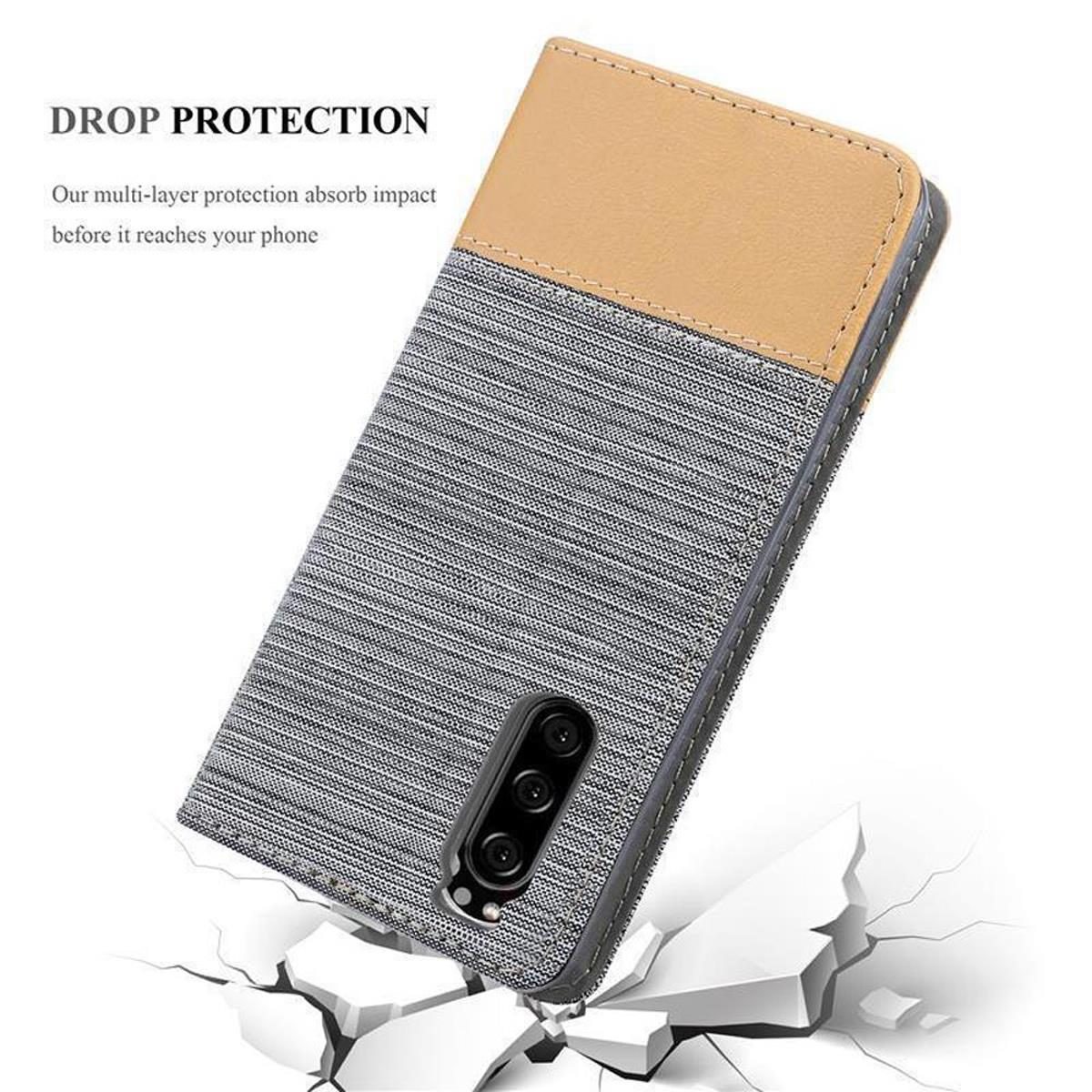 Custodia per telefono, grigio strutturato e parte superiore beige, che mostra un telefono. È su una superficie screpolata.